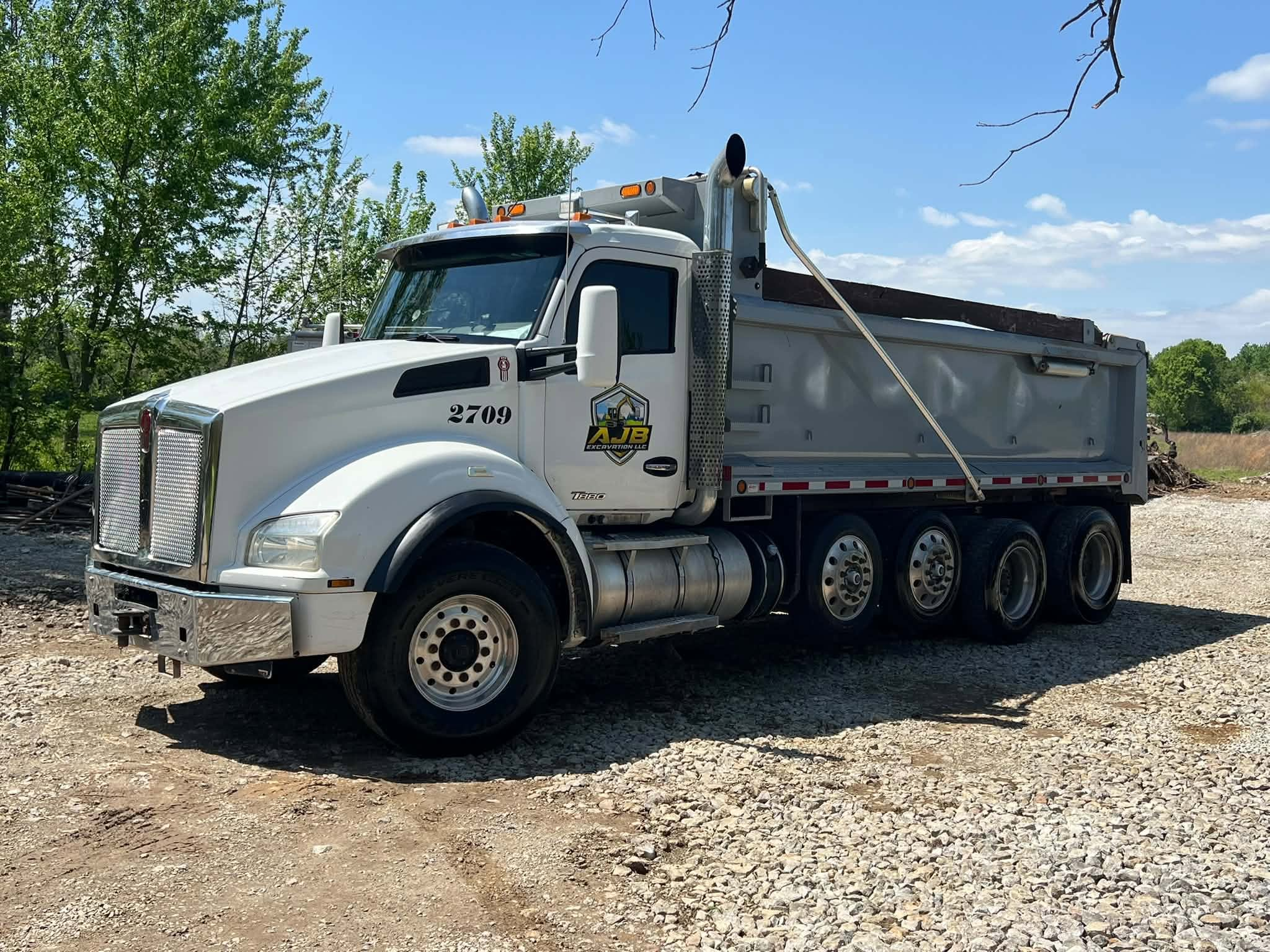 AJB Excavation LLC branded Kenworth dump truck #2709 with company logo on gravel job site