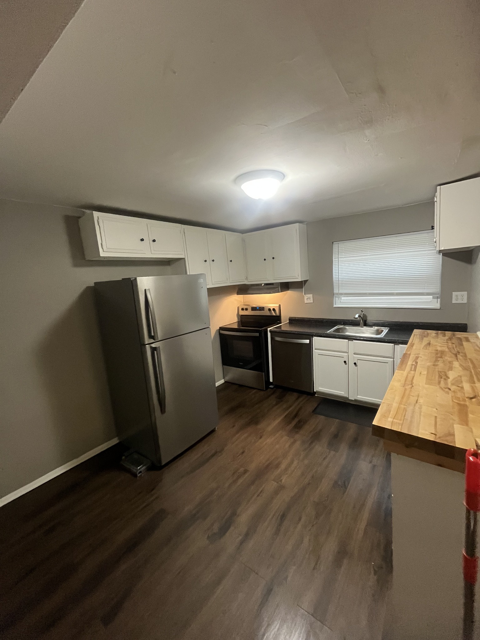 Spotless move-out cleaned kitchen with stainless refrigerator, stove, dishwasher, and wood-look floors