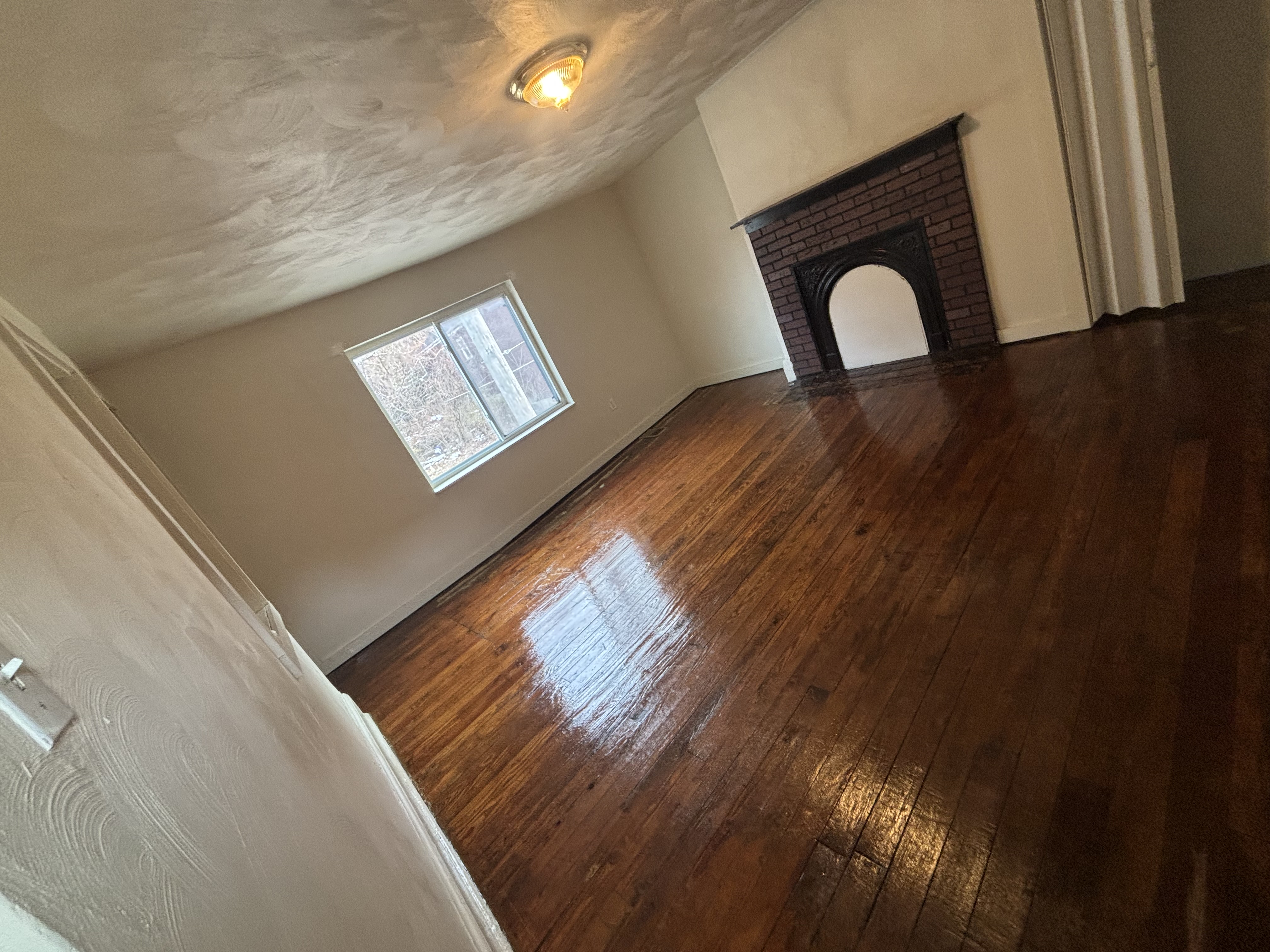 Empty move-out cleaned room with spotless gleaming hardwood floors and fireplace