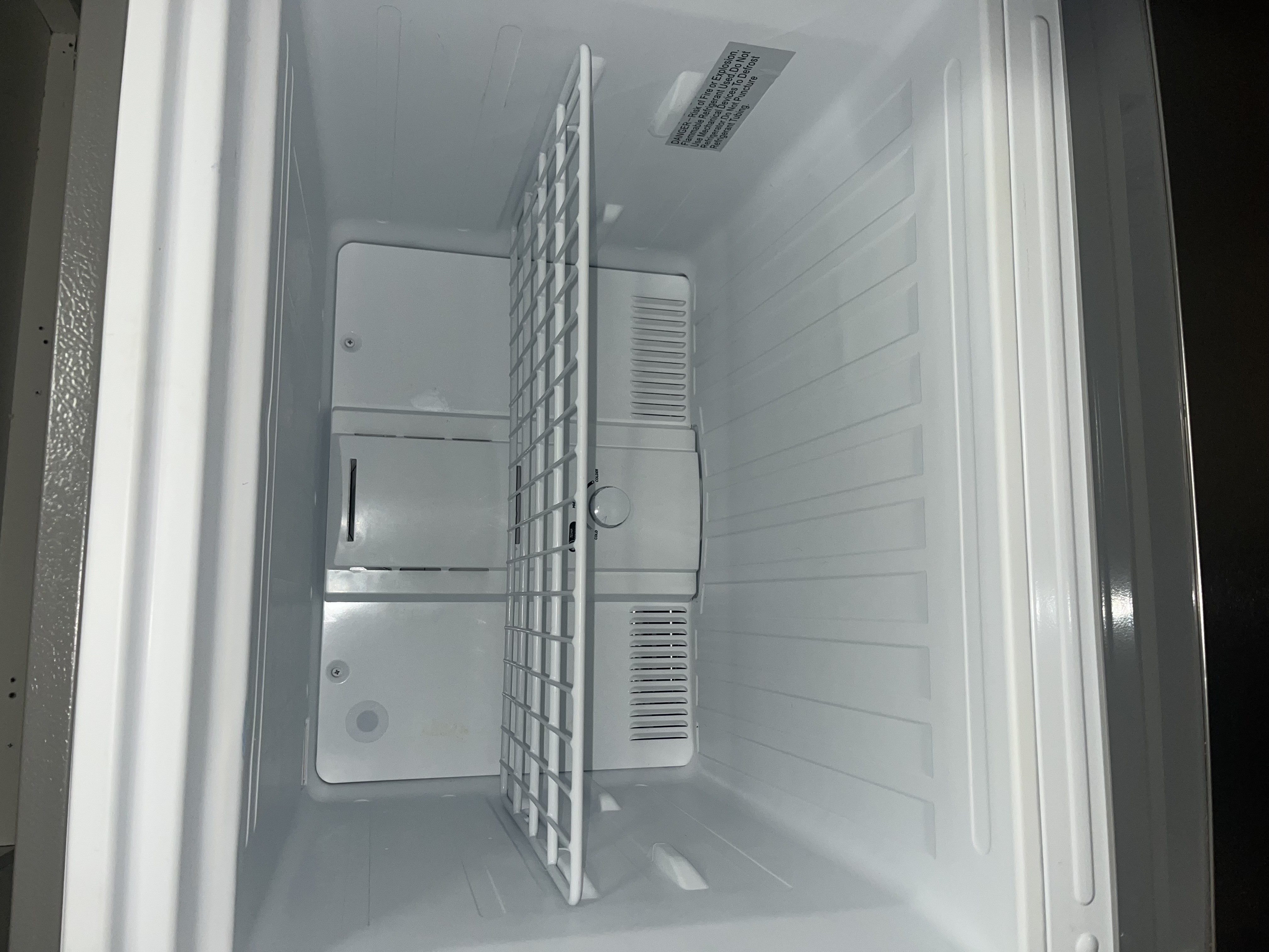 Immaculately clean inside of freezer compartment with wire shelf wiped clean