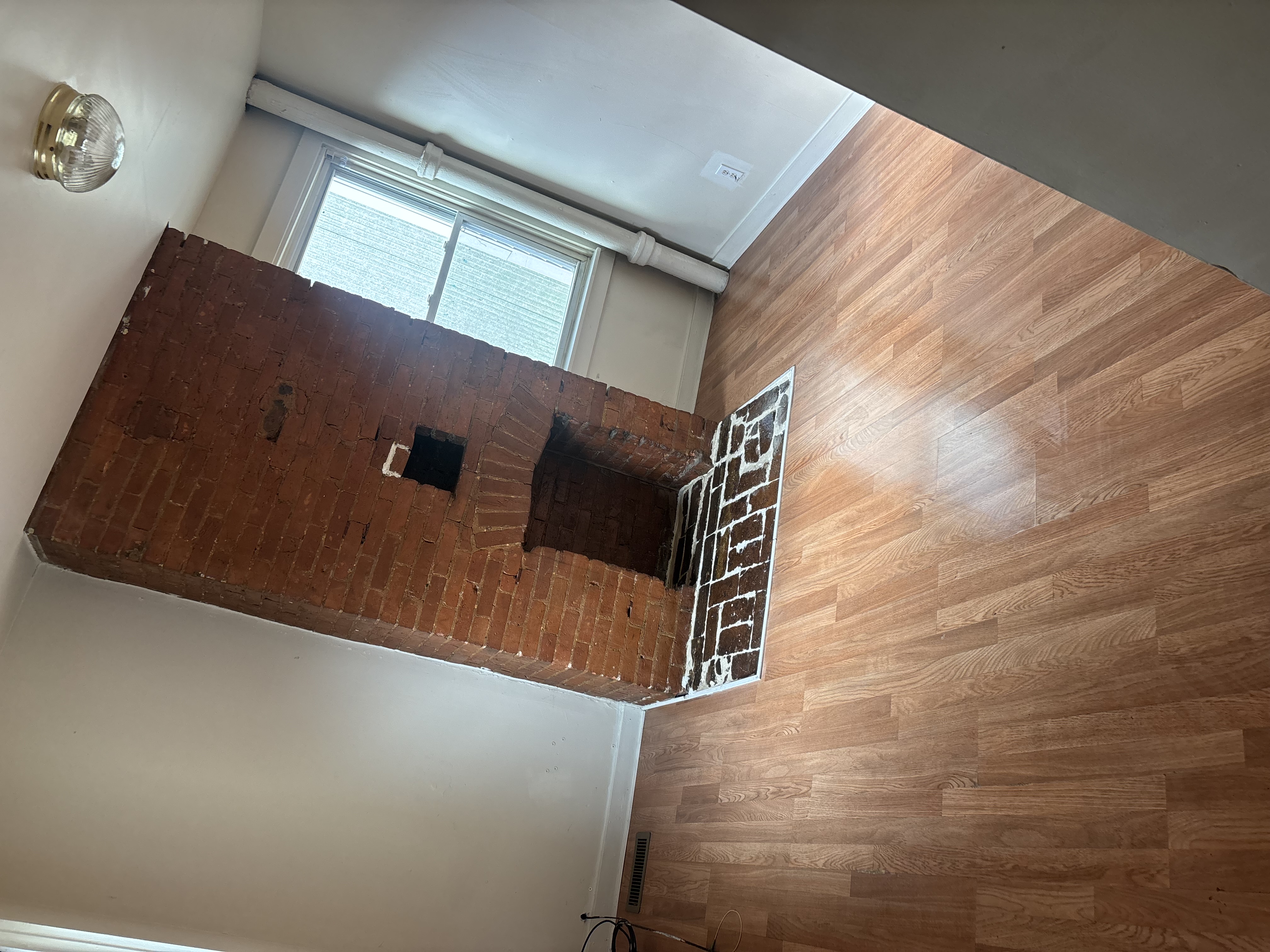 Vacated rental unit with swept and mopped laminate floors and clean brick chimney column