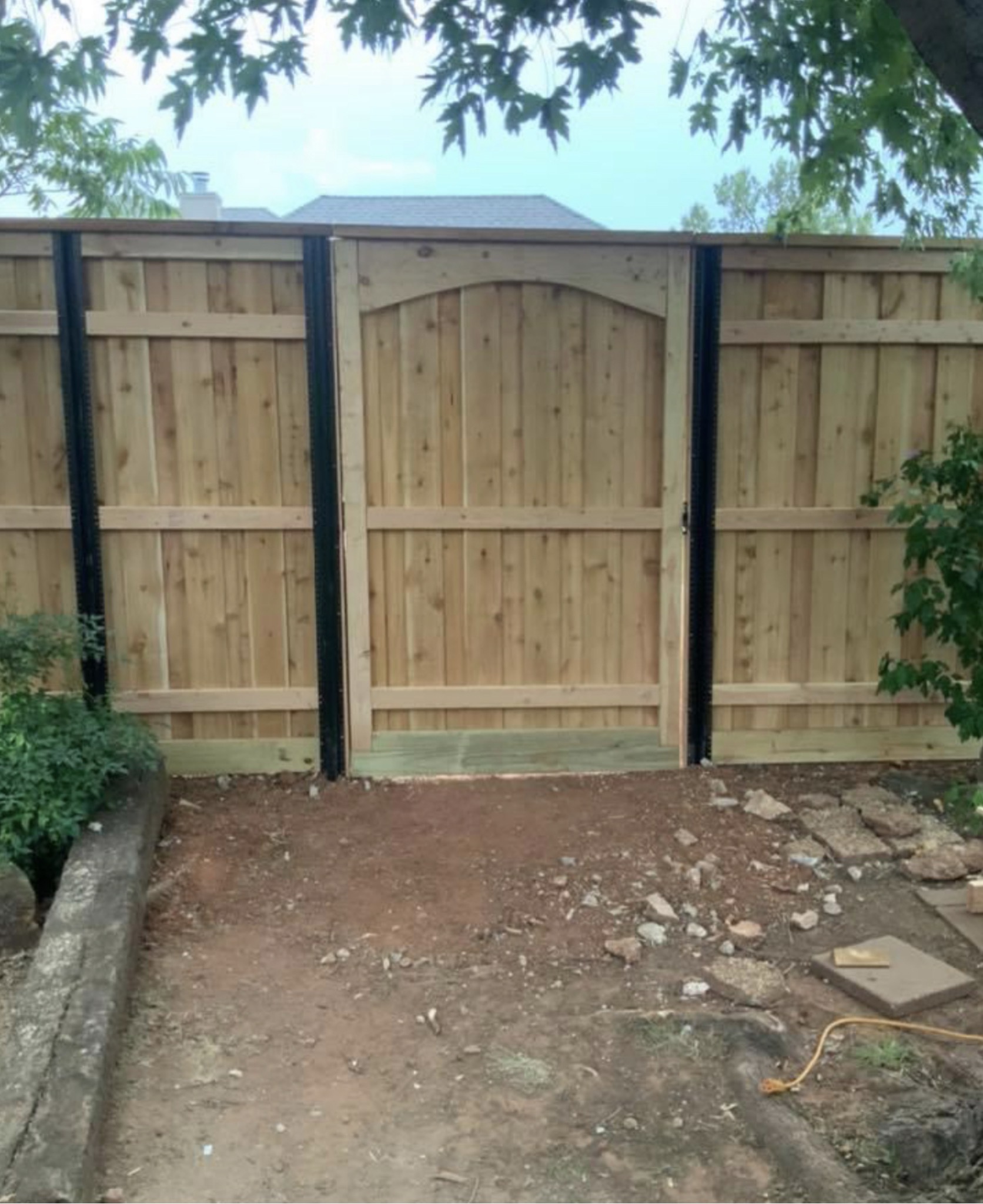 Western Red Cedar wood walk gate with decorative arch top and heavy-duty black steel framing posts.