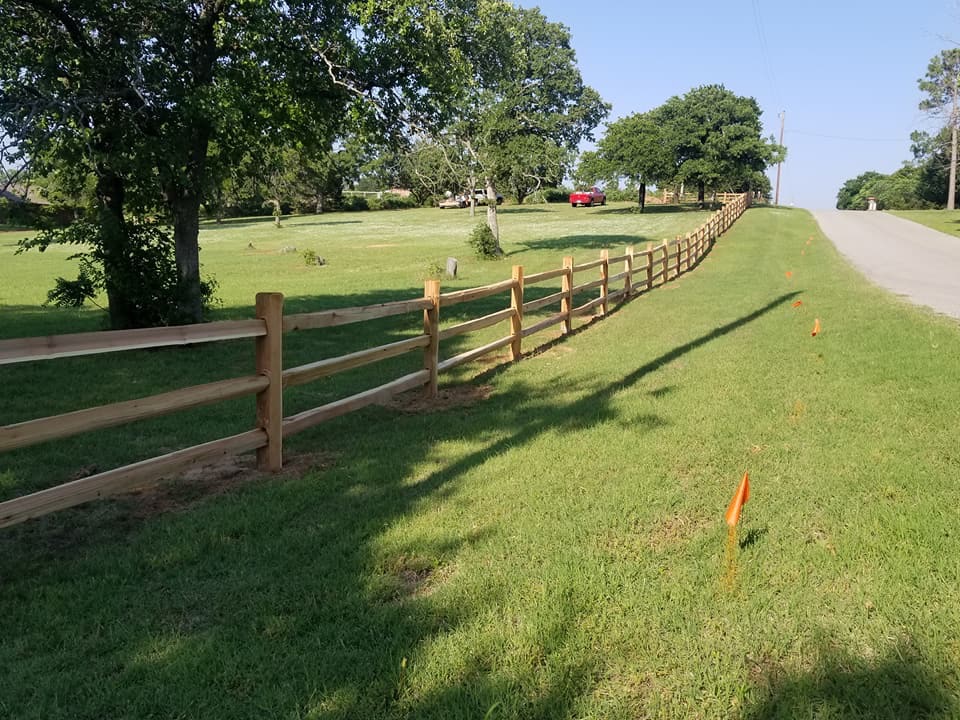 Three-rail cedar split rail fence gently following the natural contour of an open lawn and roadside.