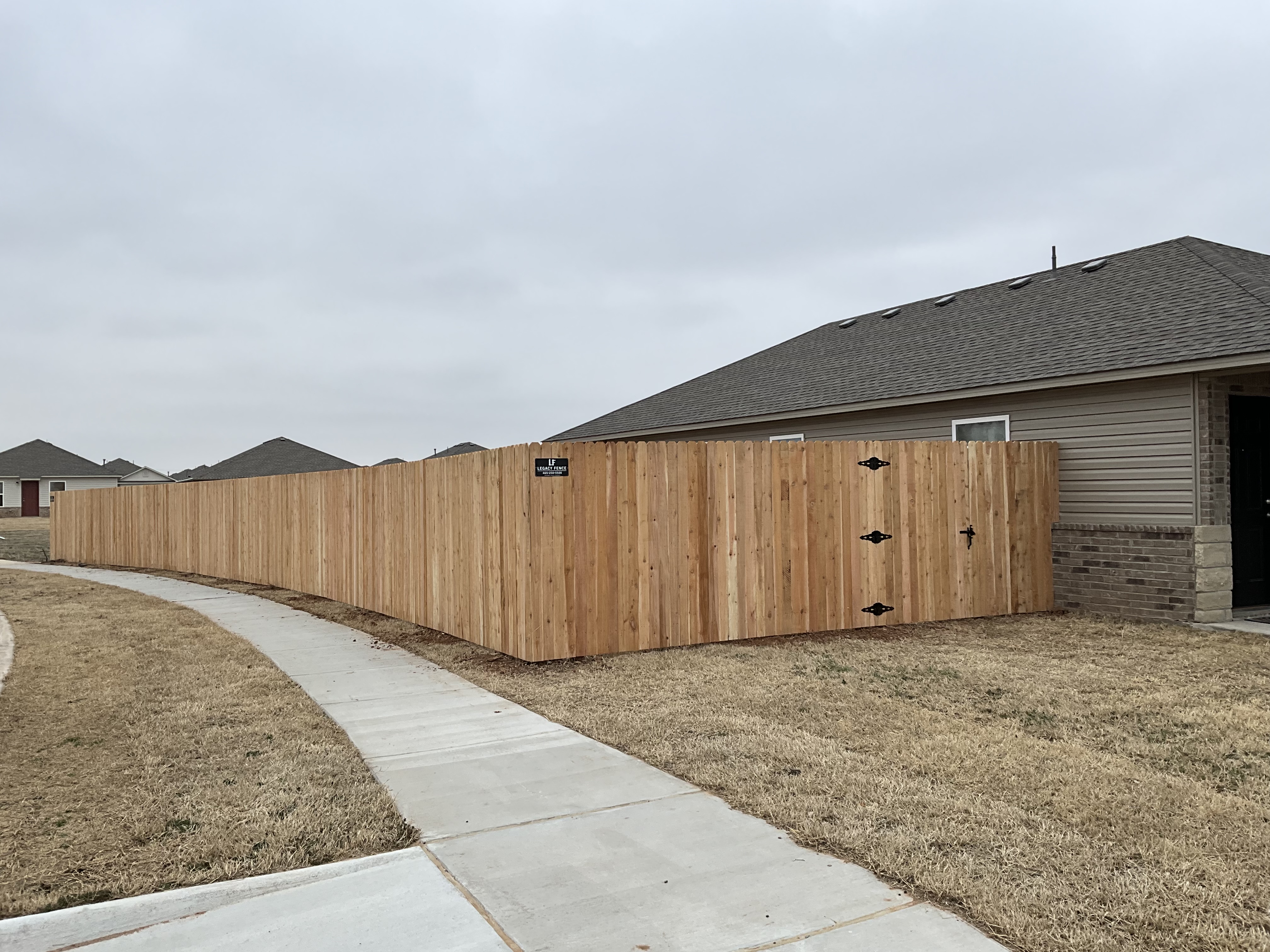 Western Red Cedar wood privacy fence with clean line along sidewalk and corner walk gate.