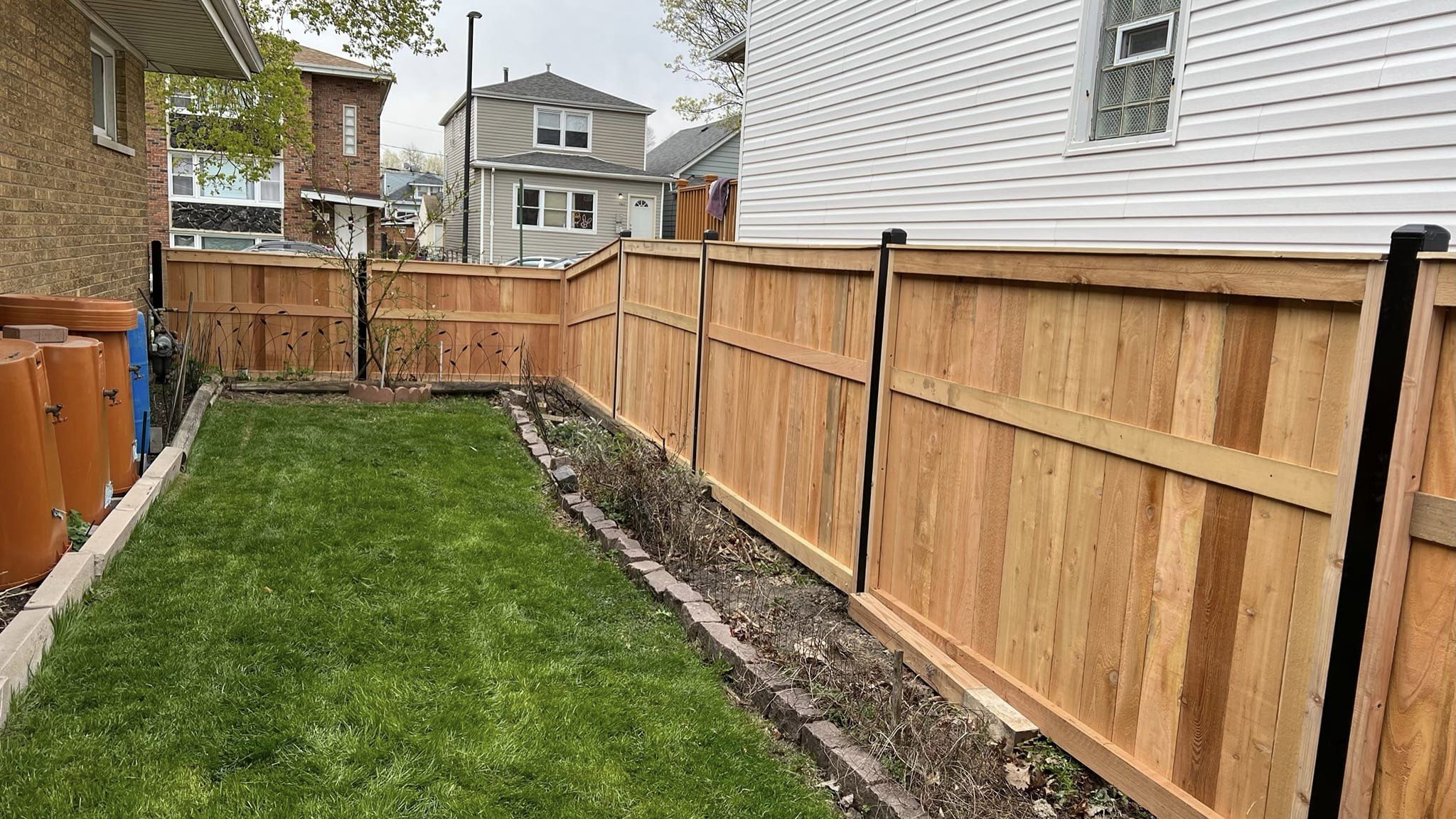 Real backyard custom cedar wood fence installation with metal posts by Dougy Construction