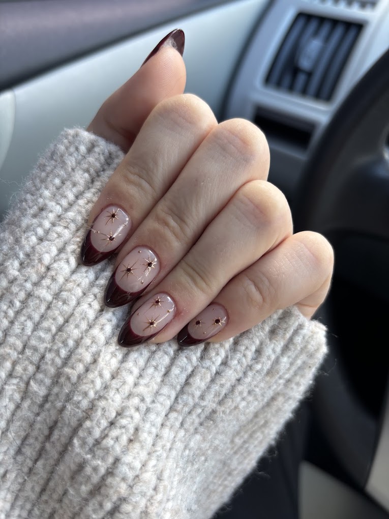 French manicure with gold star details on burgundy tips