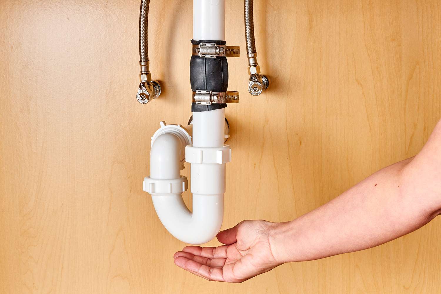 Plumber using electronic leak detection equipment on pipes under a sink in a Leesburg home