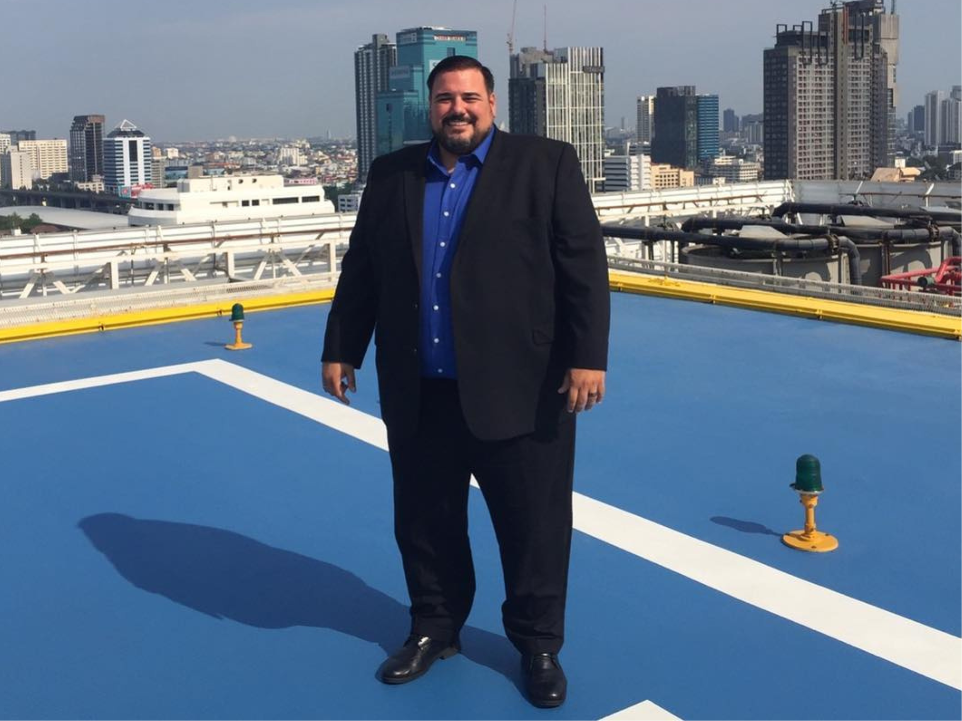 Diego on a helipad with city skyline — business and leadership context