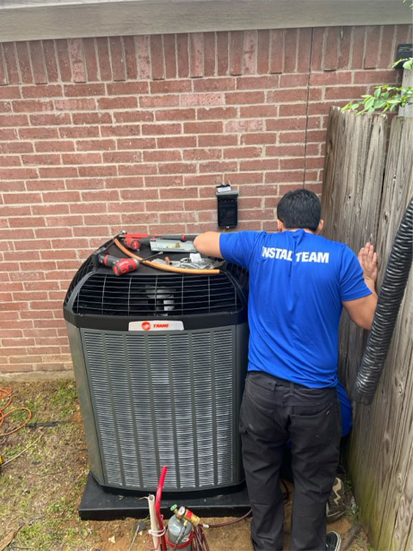 Service Champs technician servicing outdoor heat pump condenser unit