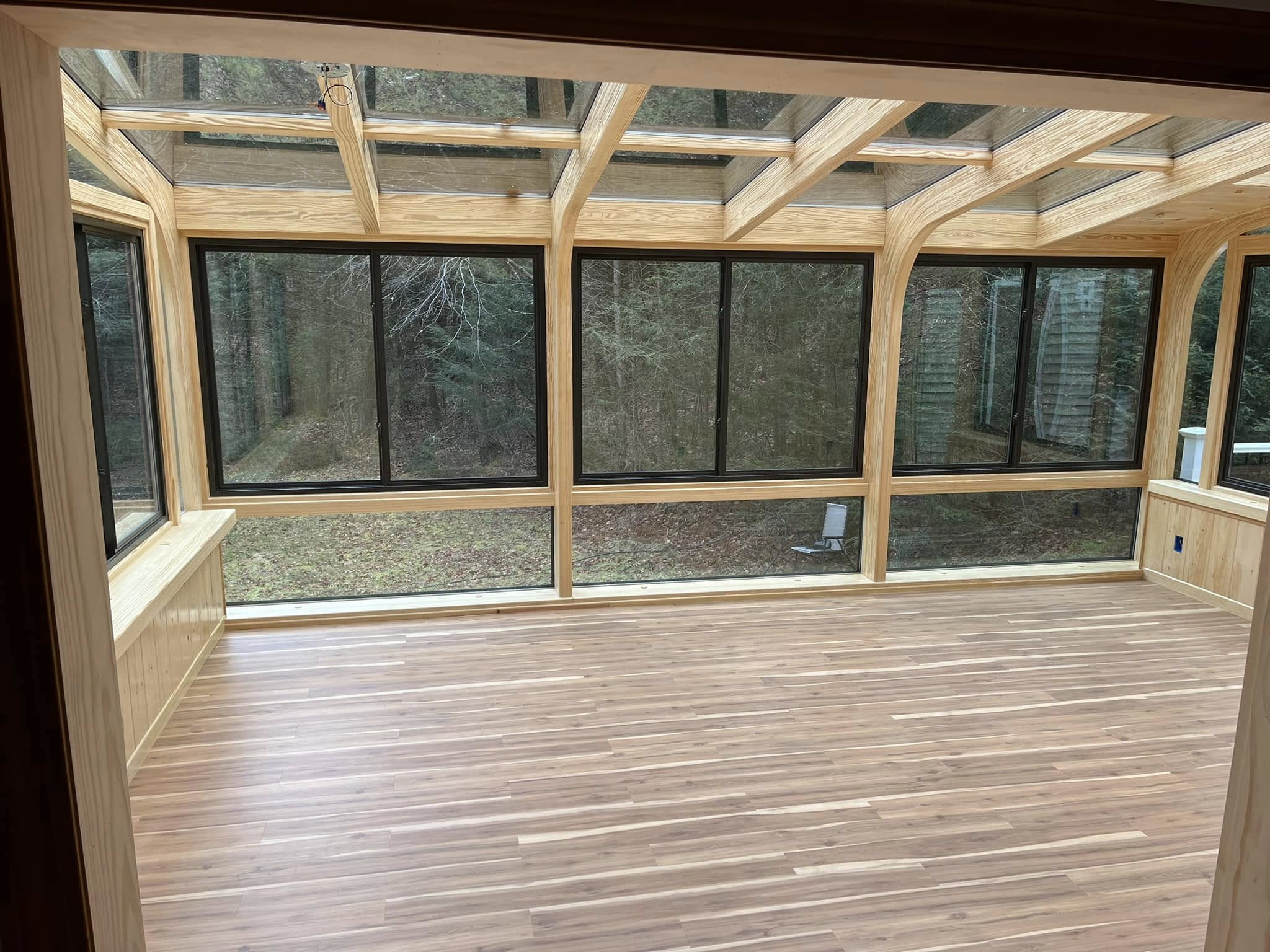 Deck or porch project by Handy Lou's — sunroom interior with curved wooden beams