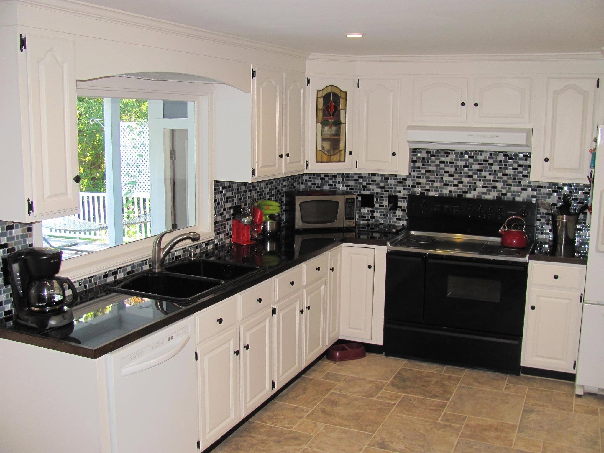 Kitchen remodel by Handy Lou's — white cabinets with black mosaic tile backsplash and dark countertops