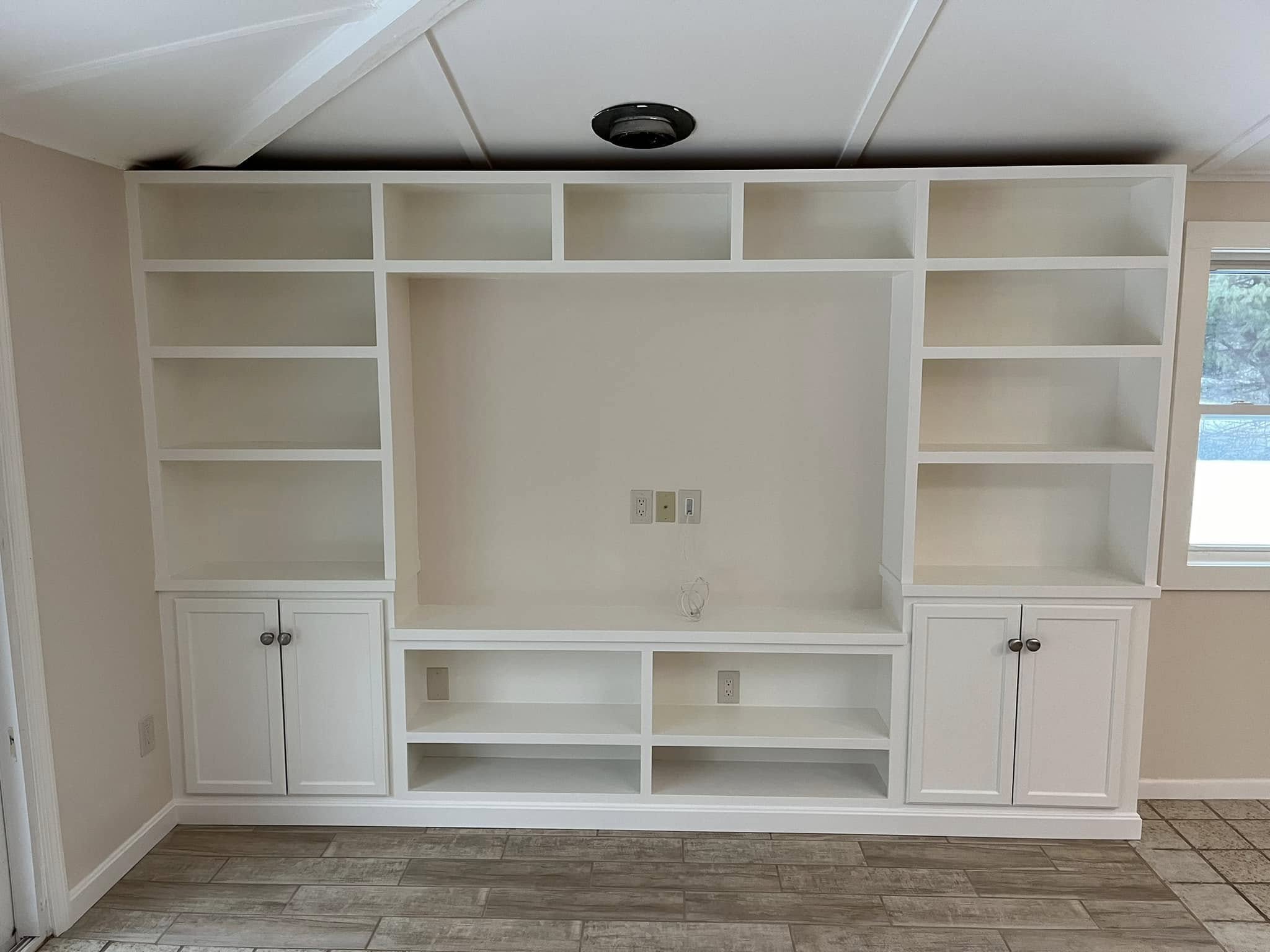 Custom woodwork by Handy Lou's — floor-to-ceiling bathroom storage cabinet with open doors