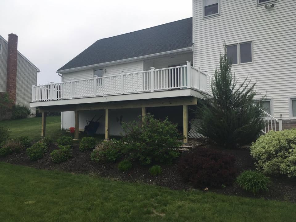 Deck or porch project by Handy Lou's — white elevated deck with landscaping