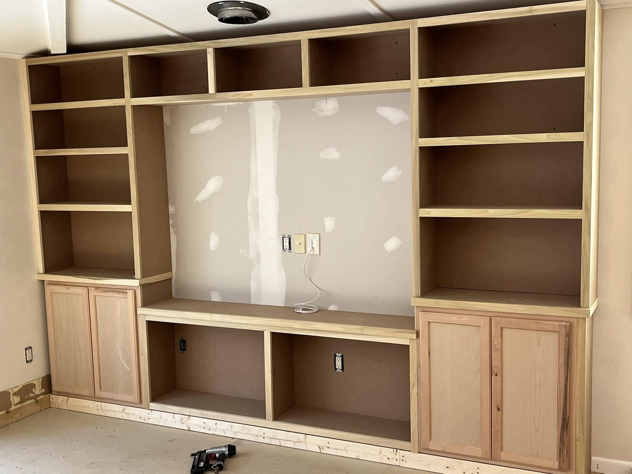 Custom woodwork by Handy Lou's — white painted bookcase shelving under staircase