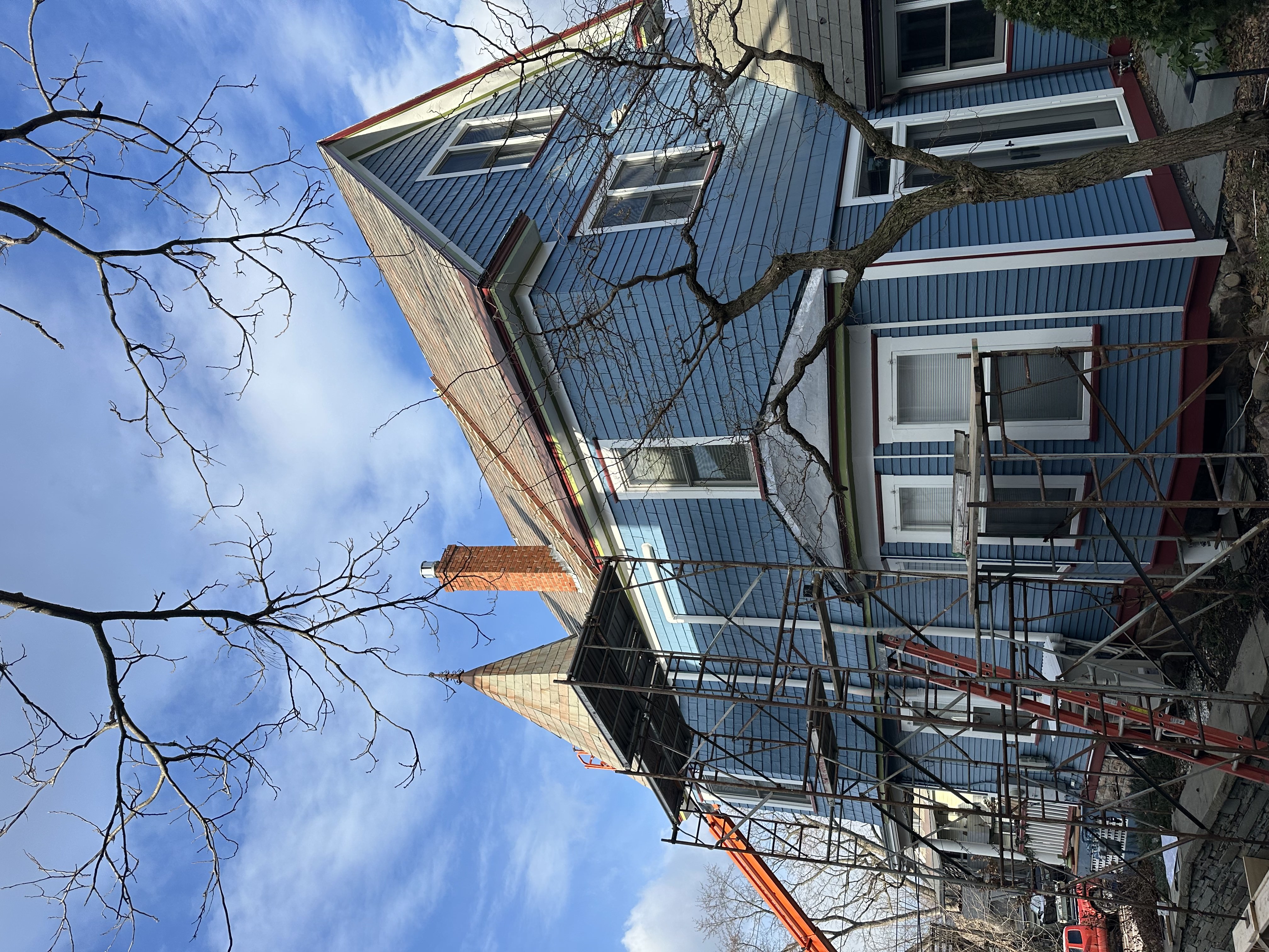 Blue Victorian home with slate roof and scaffolding during restoration