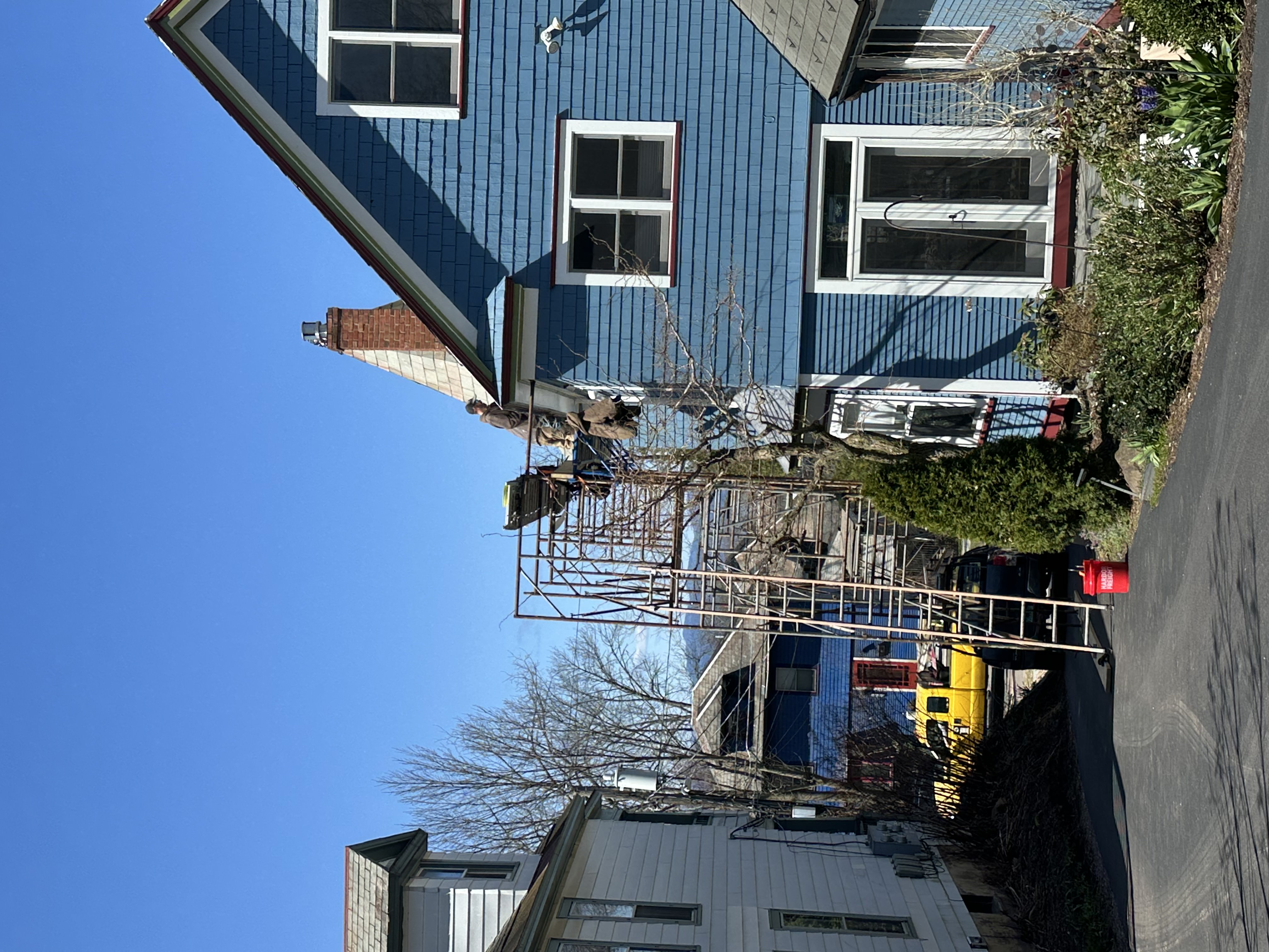 Full exterior renovation with blue siding and new slate roof in progress
