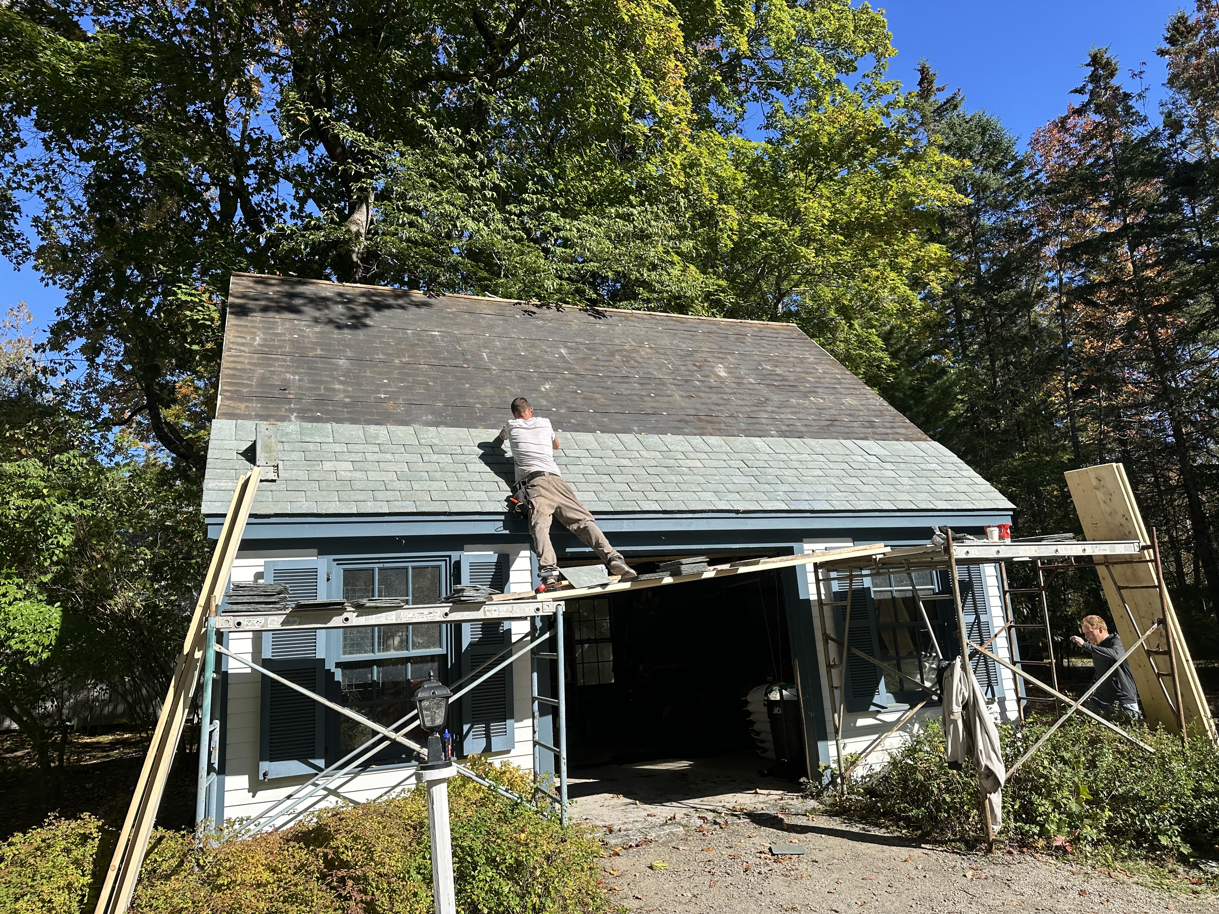 Roofer installing slate tiles on residential home with scaffolding