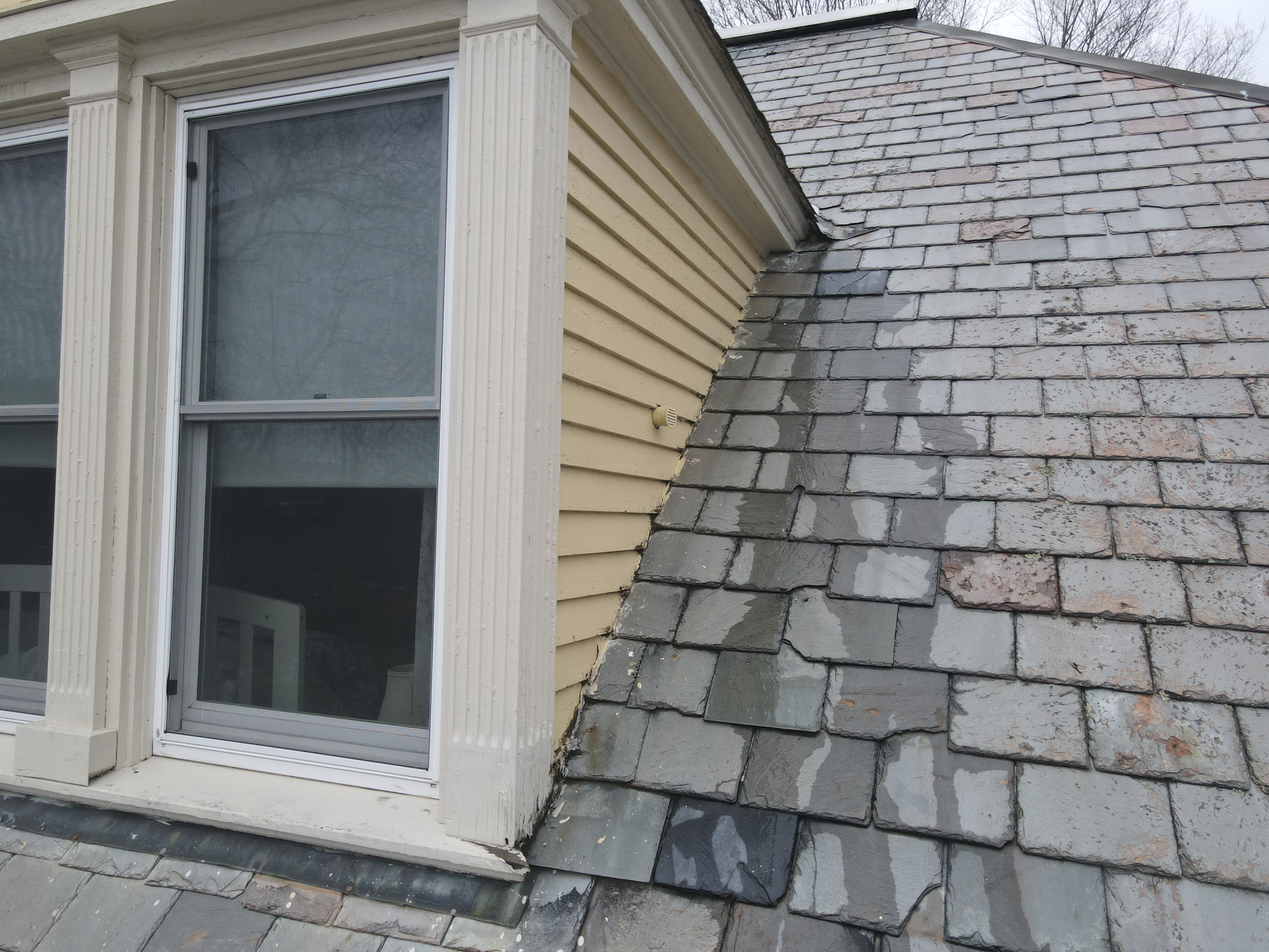 Aged slate roof with weathered natural patina on historic Vermont home with cream siding and white trim window