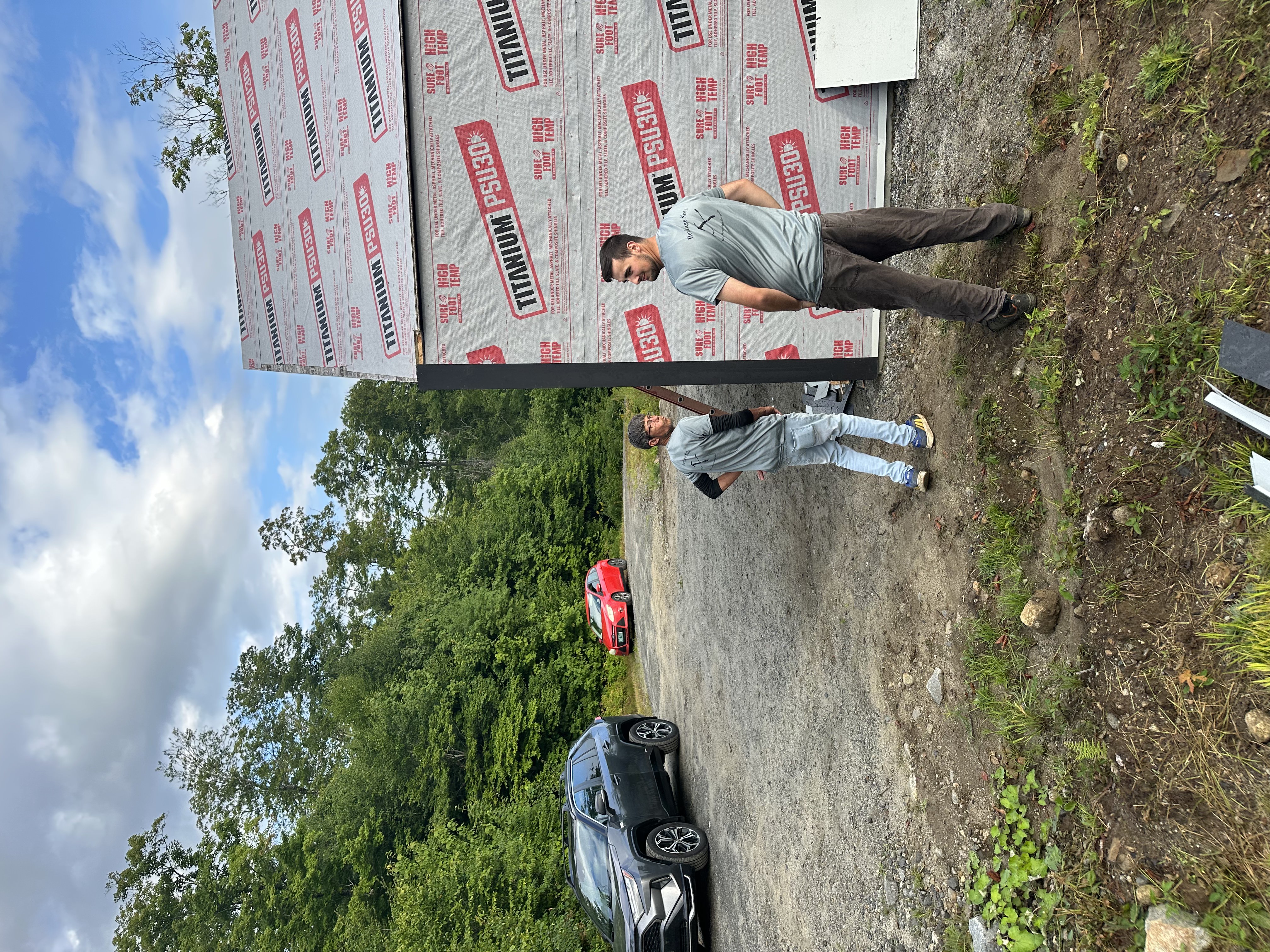 Crew members working together on roofing project in rural Vermont setting