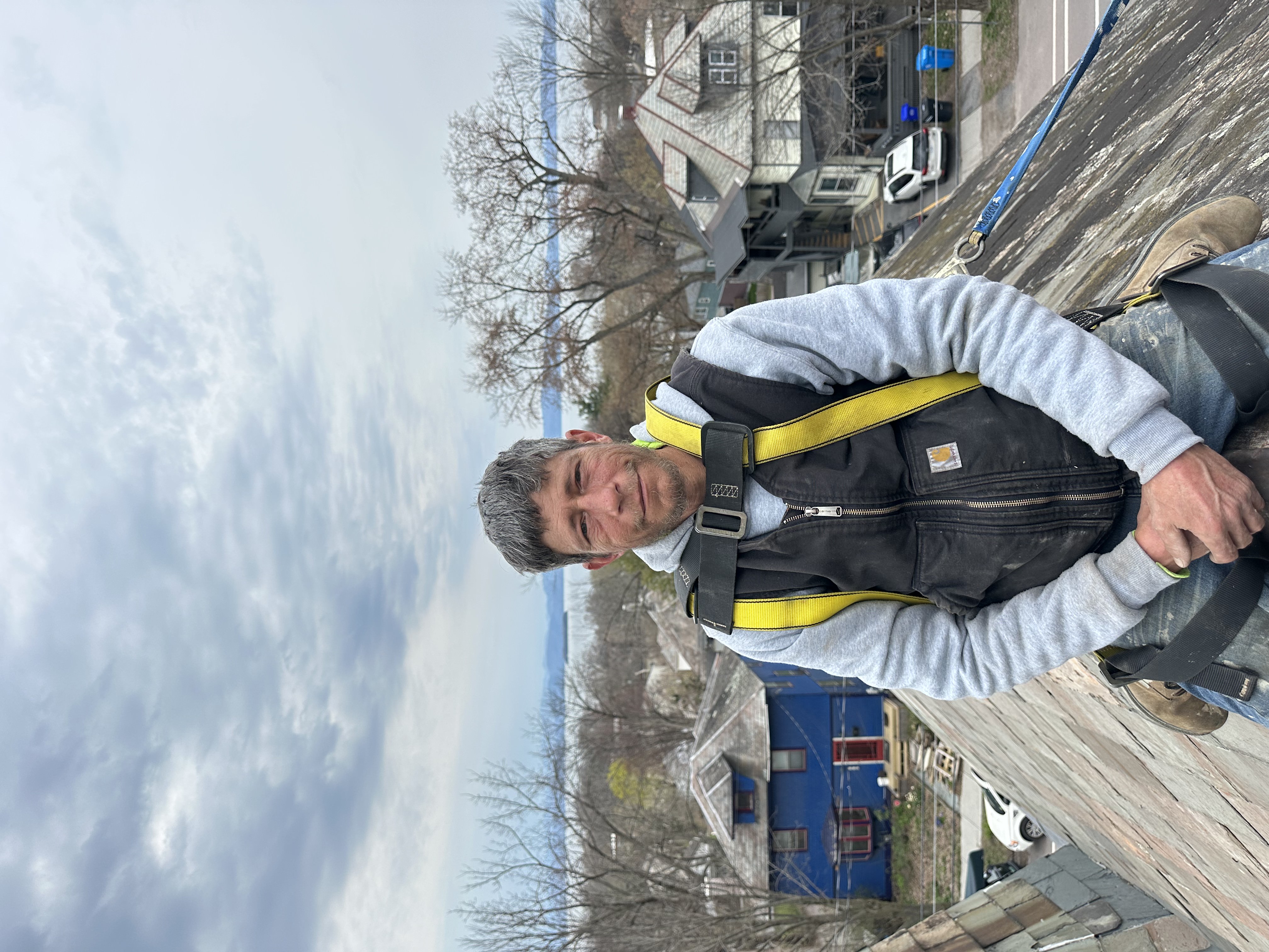 Roofer on slate roof with safety harness during installation work