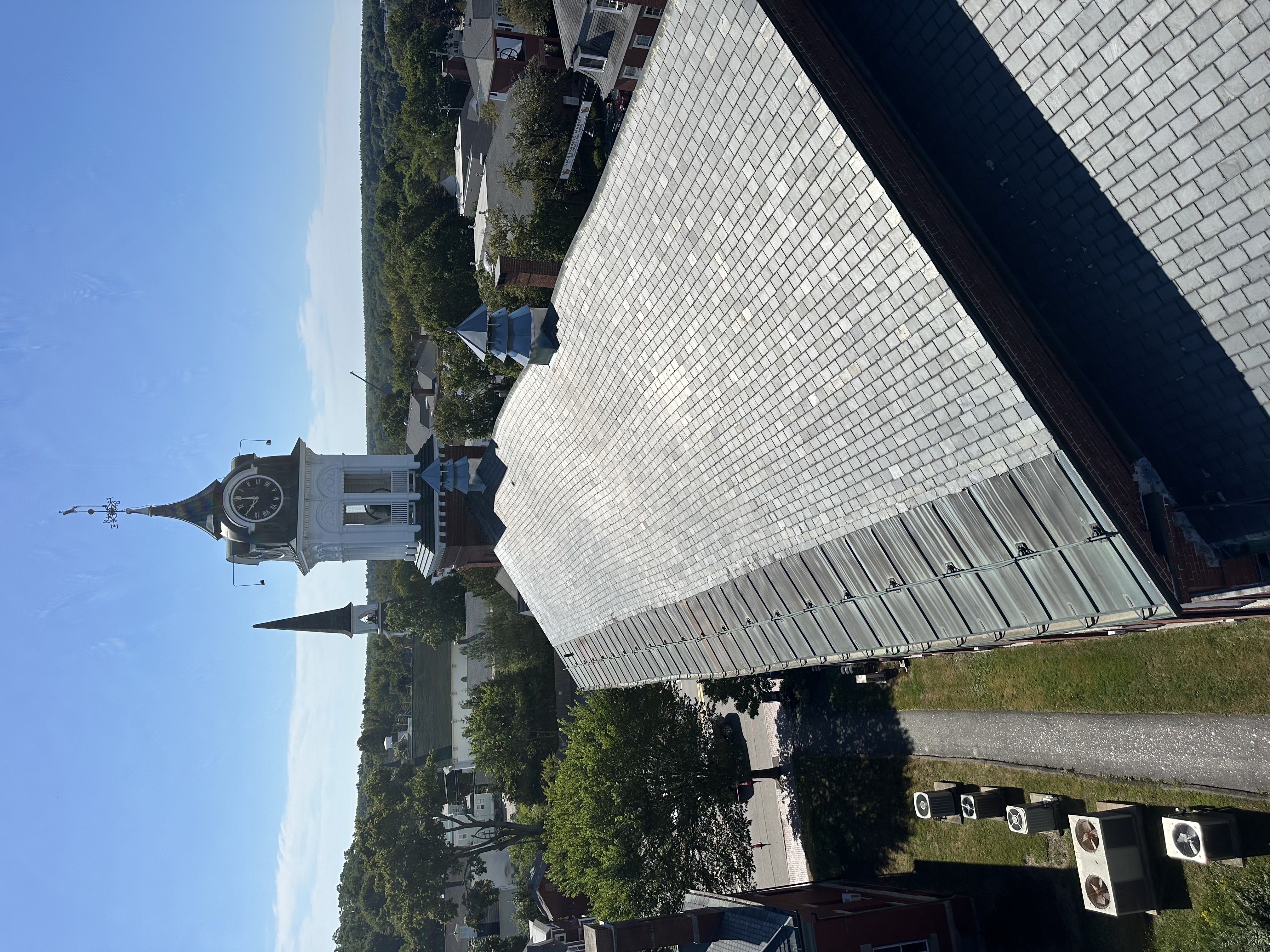 Historic church steeple and clock tower with slate roof installation in progress in Vermont town center