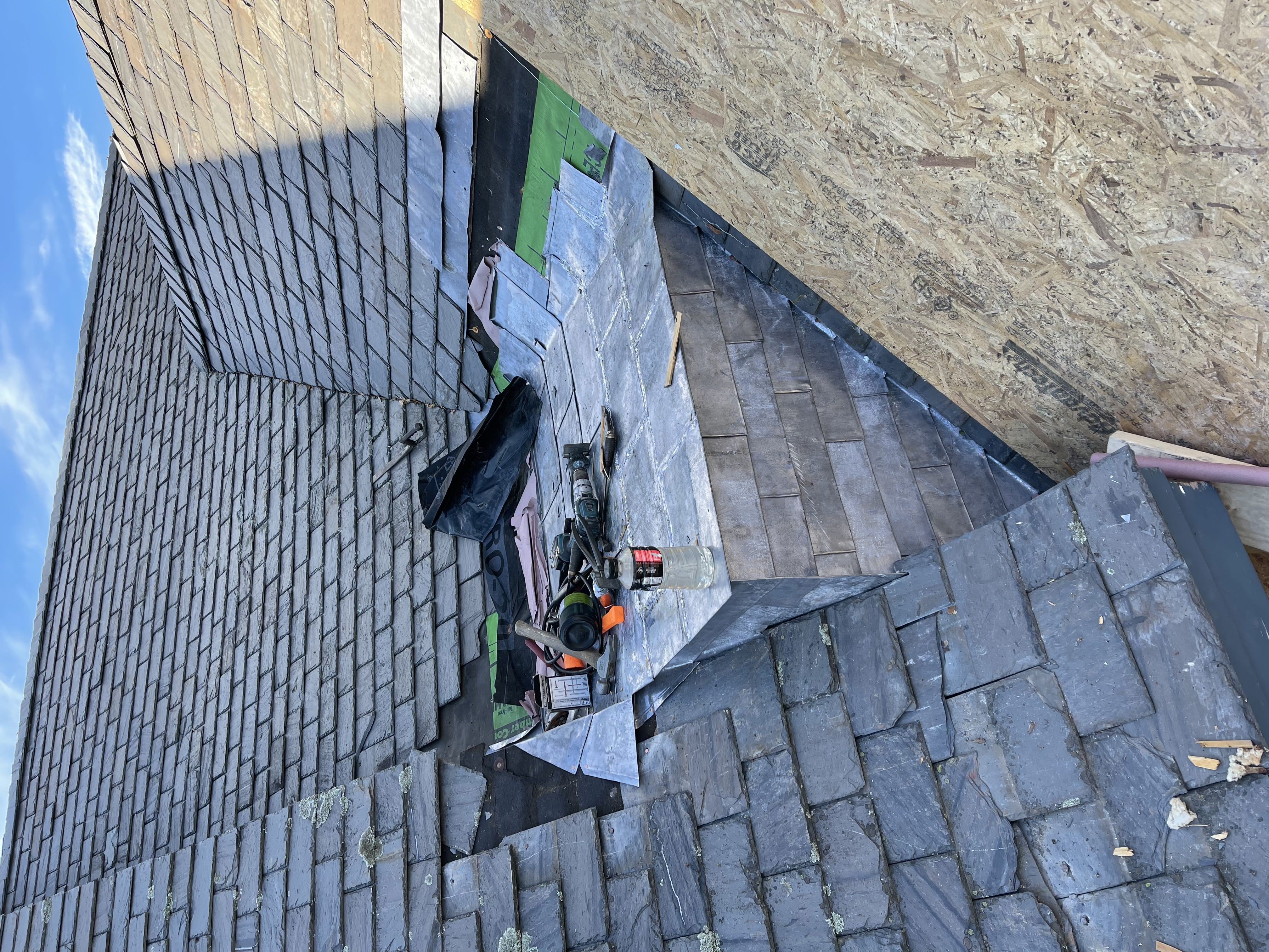Close-up of slate tile installation with tools on site