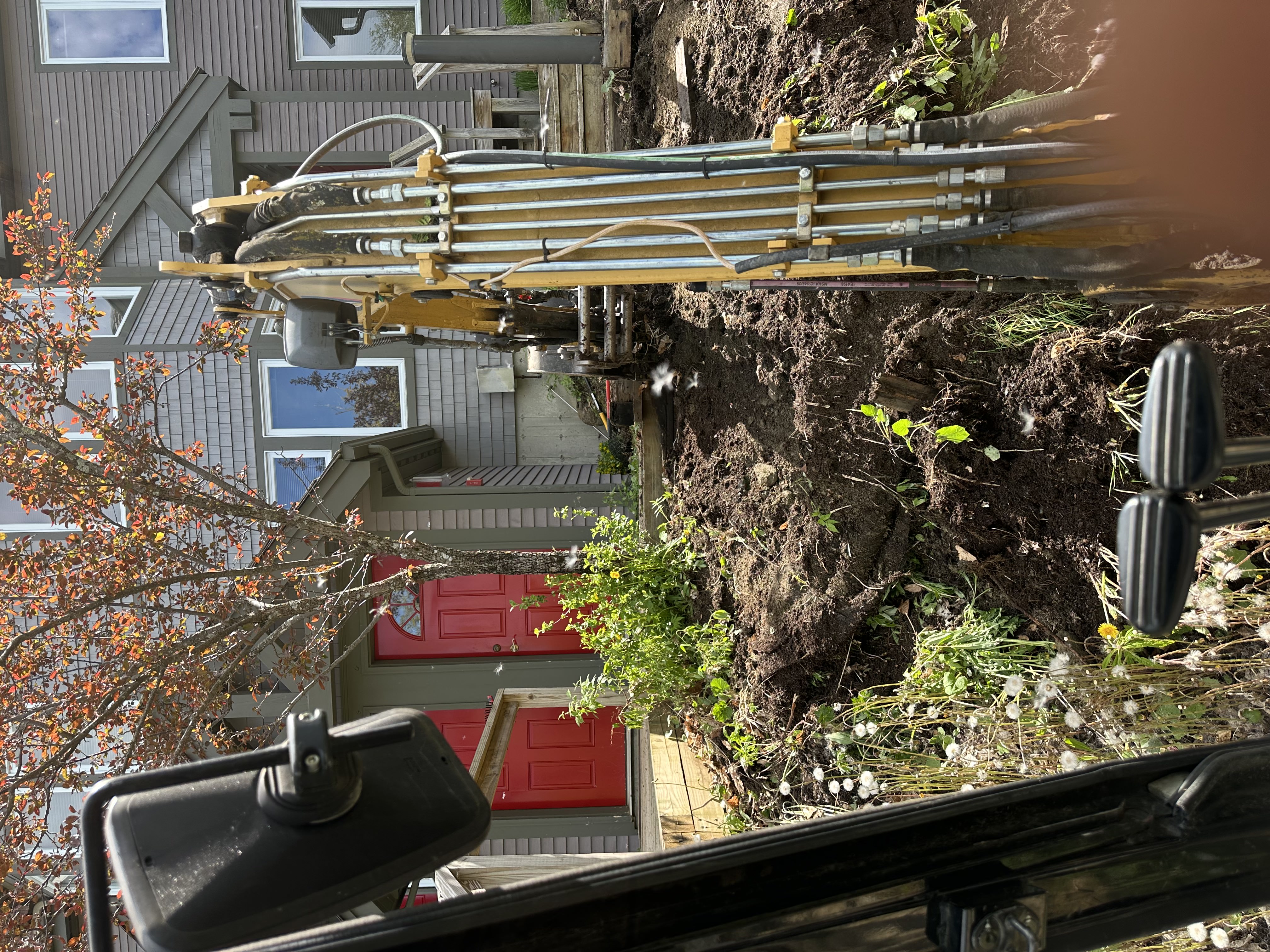 Excavation drilling equipment at Vermont residential property with red door