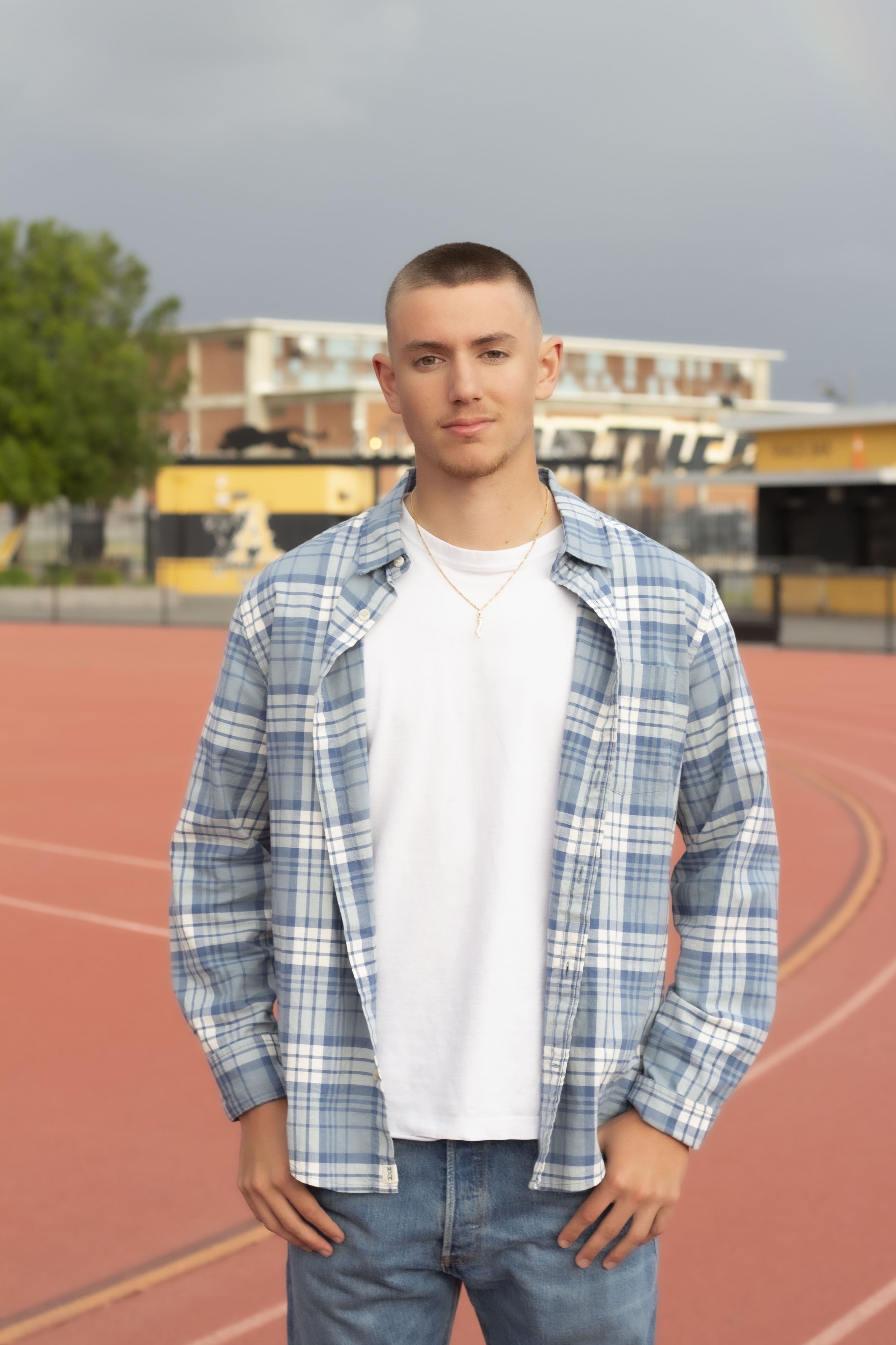 Senior standing on track field portrait by Brooke Lazzarini