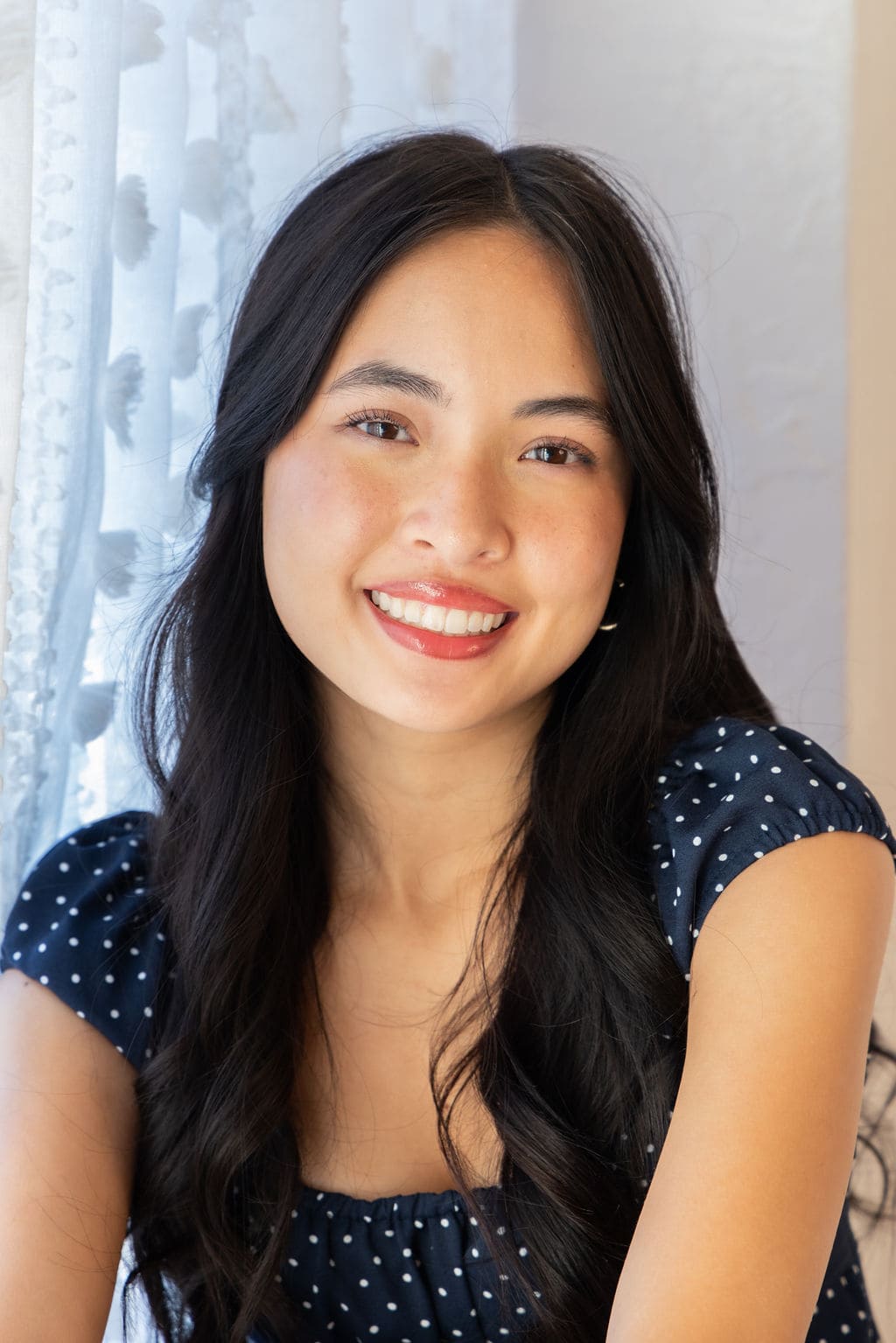 Senior in navy polka dot dress smiling portrait by Brooke Lazzarini