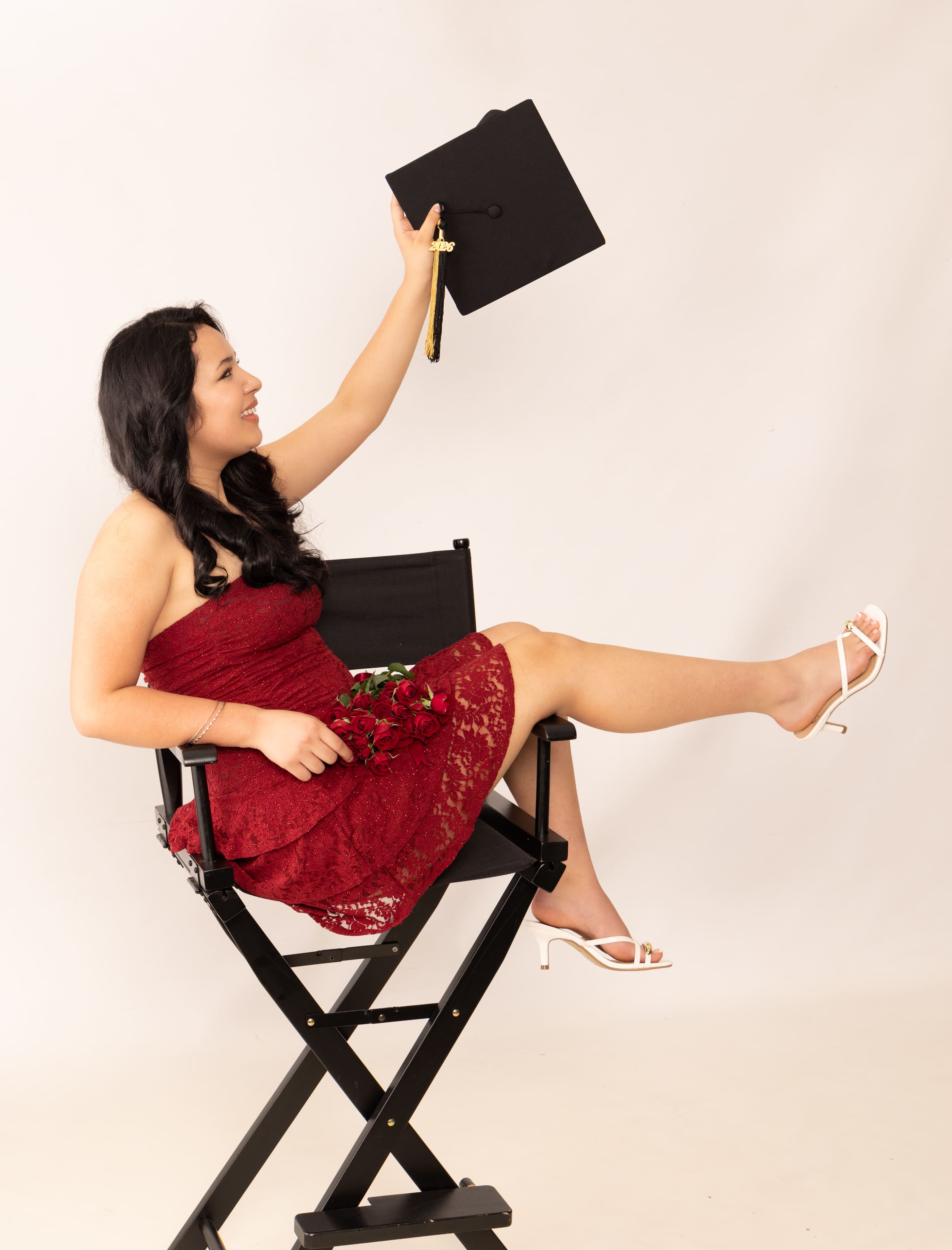 Senior in red dress holding cap with roses by Brooke Lazzarini