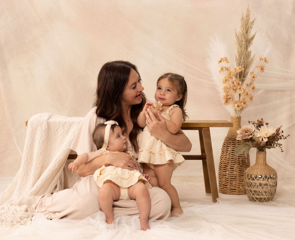 Mother holding baby with toddler by Brooke Lazzarini