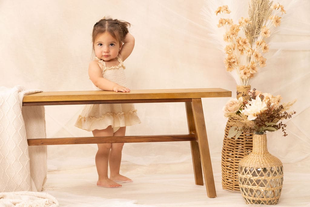 Toddler standing at wooden bench portrait by Brooke Lazzarini