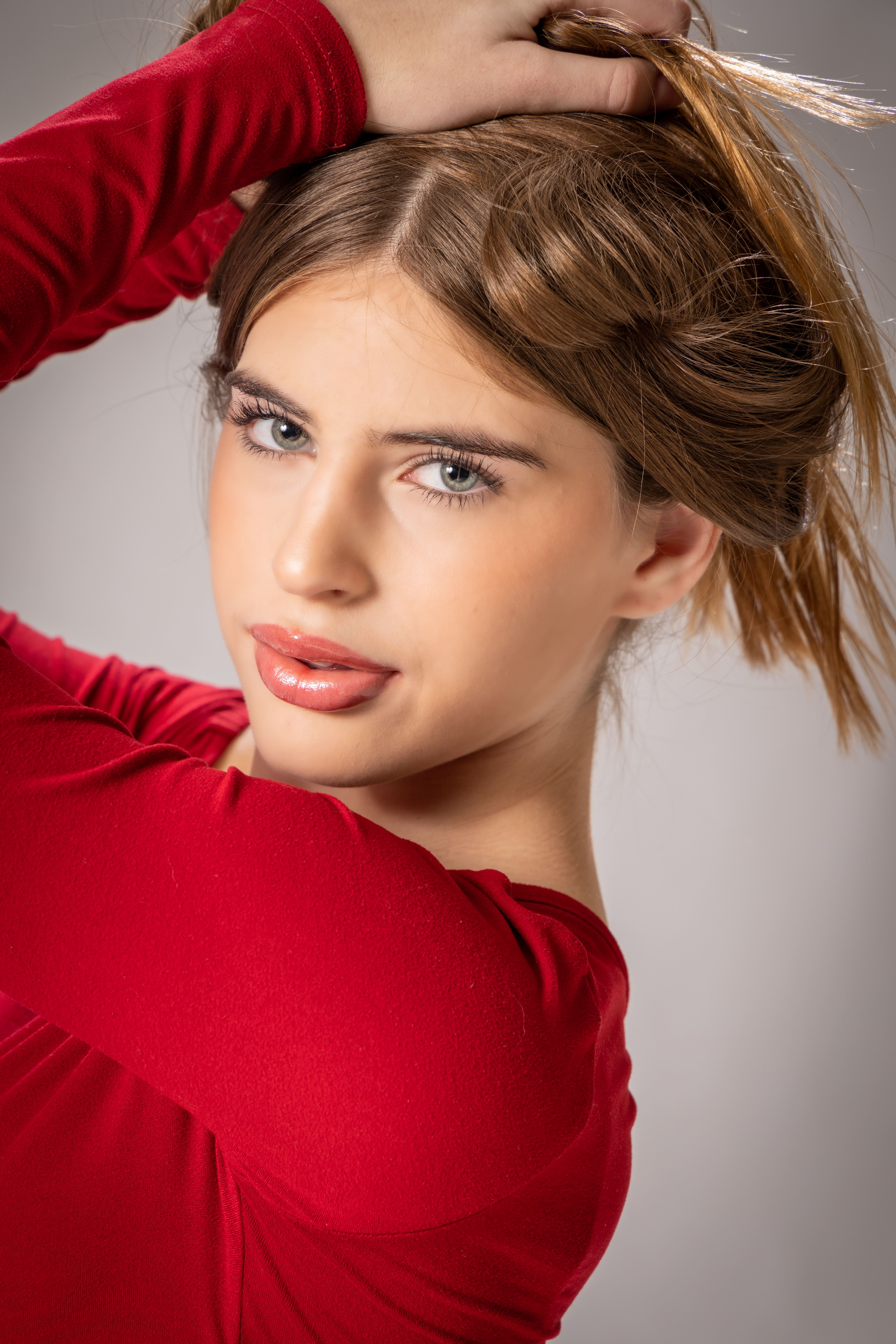 Girl in red with hand in hair close-up by Brooke Lazzarini
