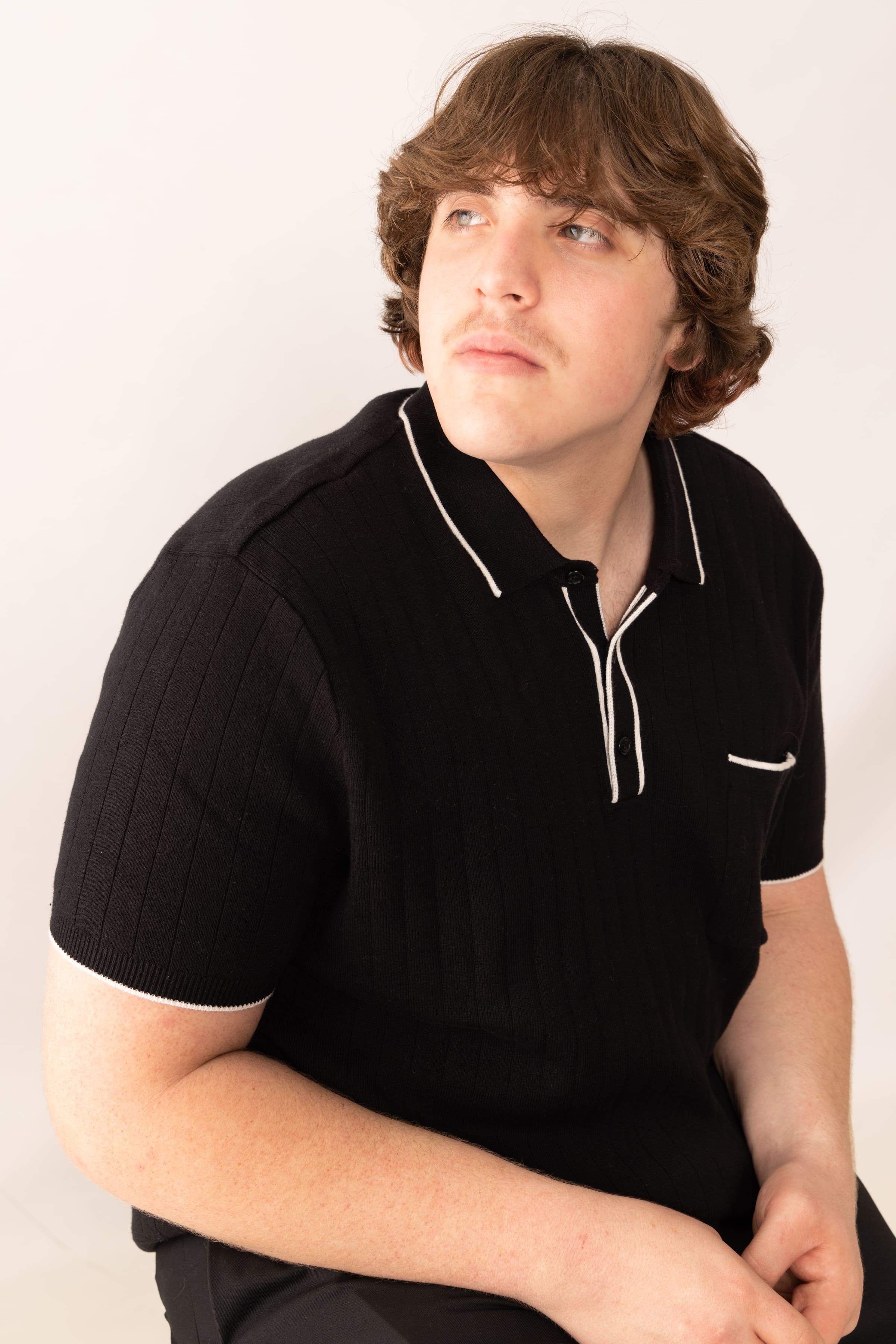 Senior in black polo studio portrait by Brooke Lazzarini