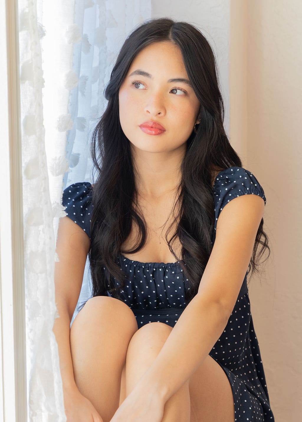Senior in navy polka dot dress looking up portrait by Brooke Lazzarini