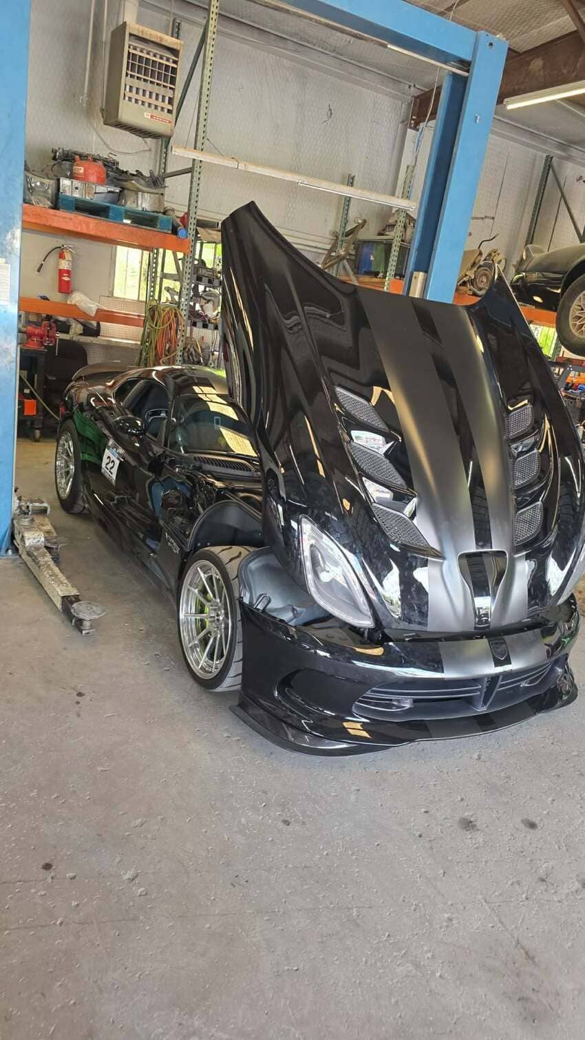 Black performance car with hood open for engine service