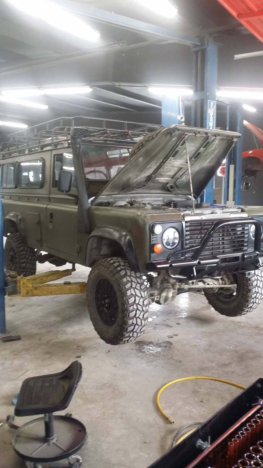Olive green Land Rover Defender on lift for engine service in our Austin bay