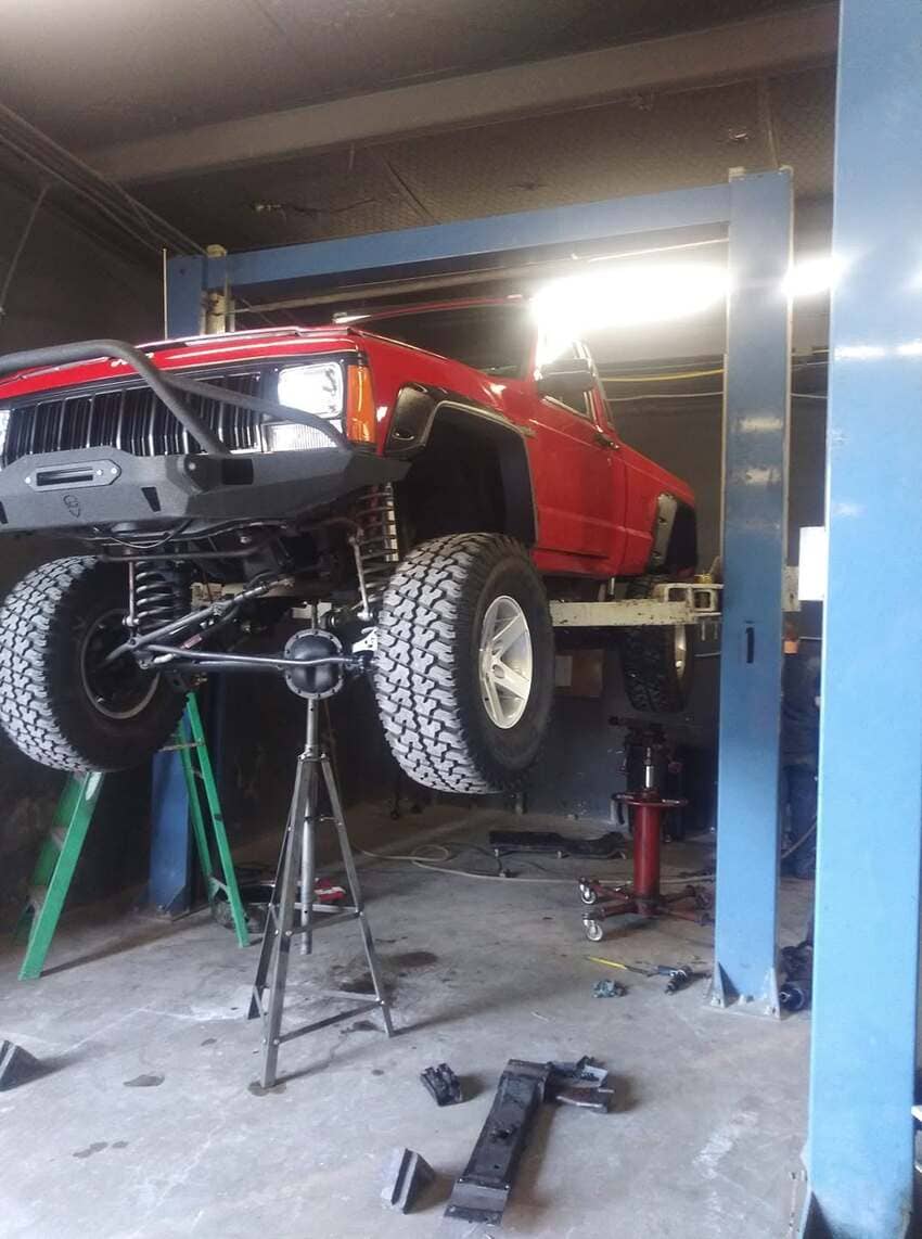 Red Jeep on lift undergoing suspension work at our Austin shop