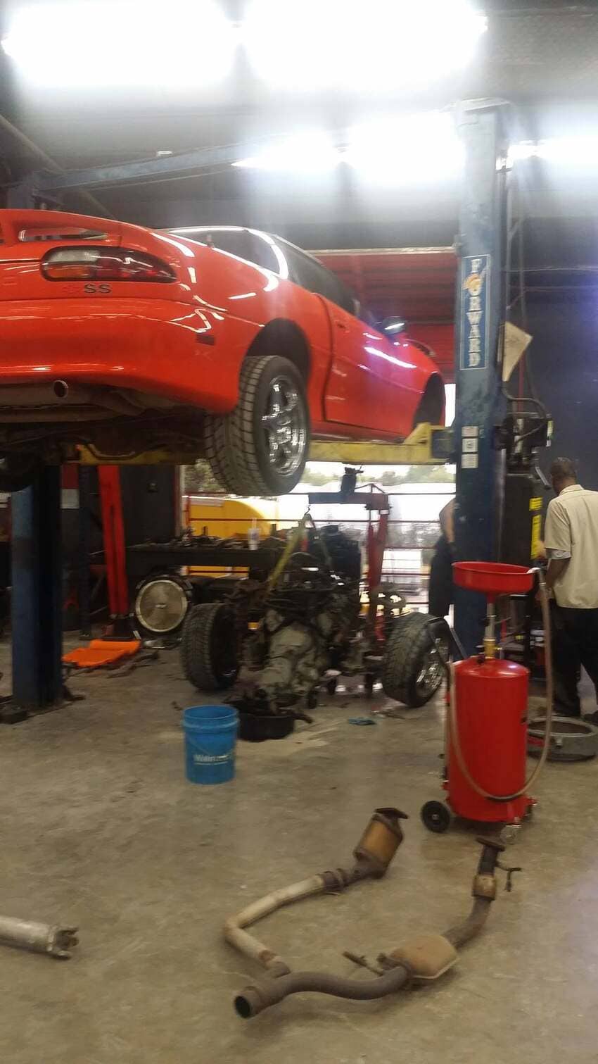 Red Camaro SS on lift during engine replacement work in our Austin service bay