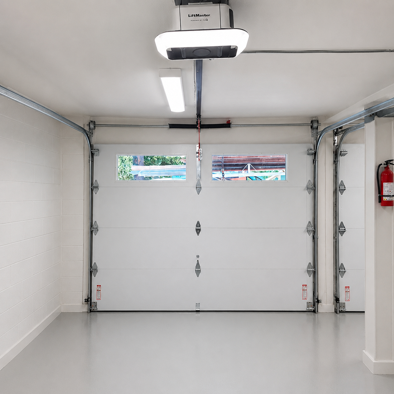 Interior view of a completed LiftMaster garage door opener installation with white sectional door and transom windows by JT Garage Doors in Santa Clara
