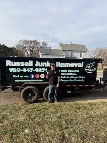 Russell Junk Removal owner next to branded junk removal truck and dumpster trailer