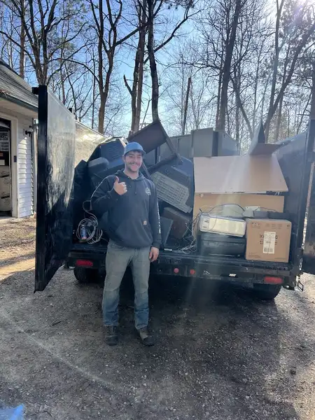 Team member giving thumbs up next to trailer fully loaded with removed junk and debris