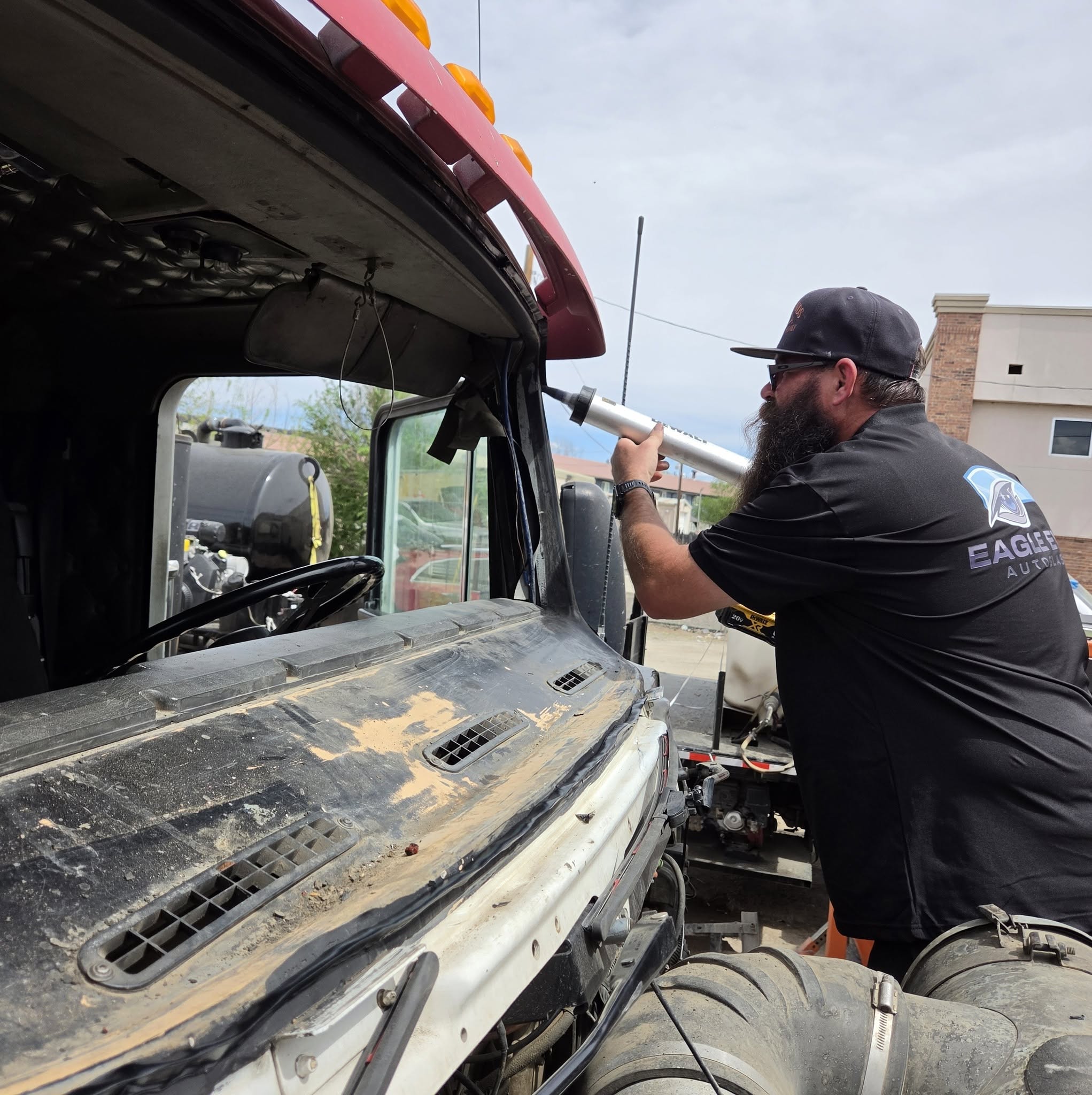 Eagle Eye technician performing windshield replacement on heavy-duty semi truck cab