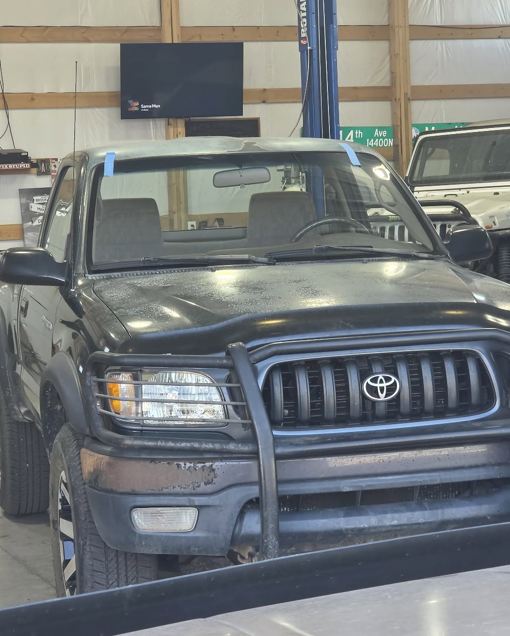 Black Toyota Tacoma with freshly installed OEM windshield in shop