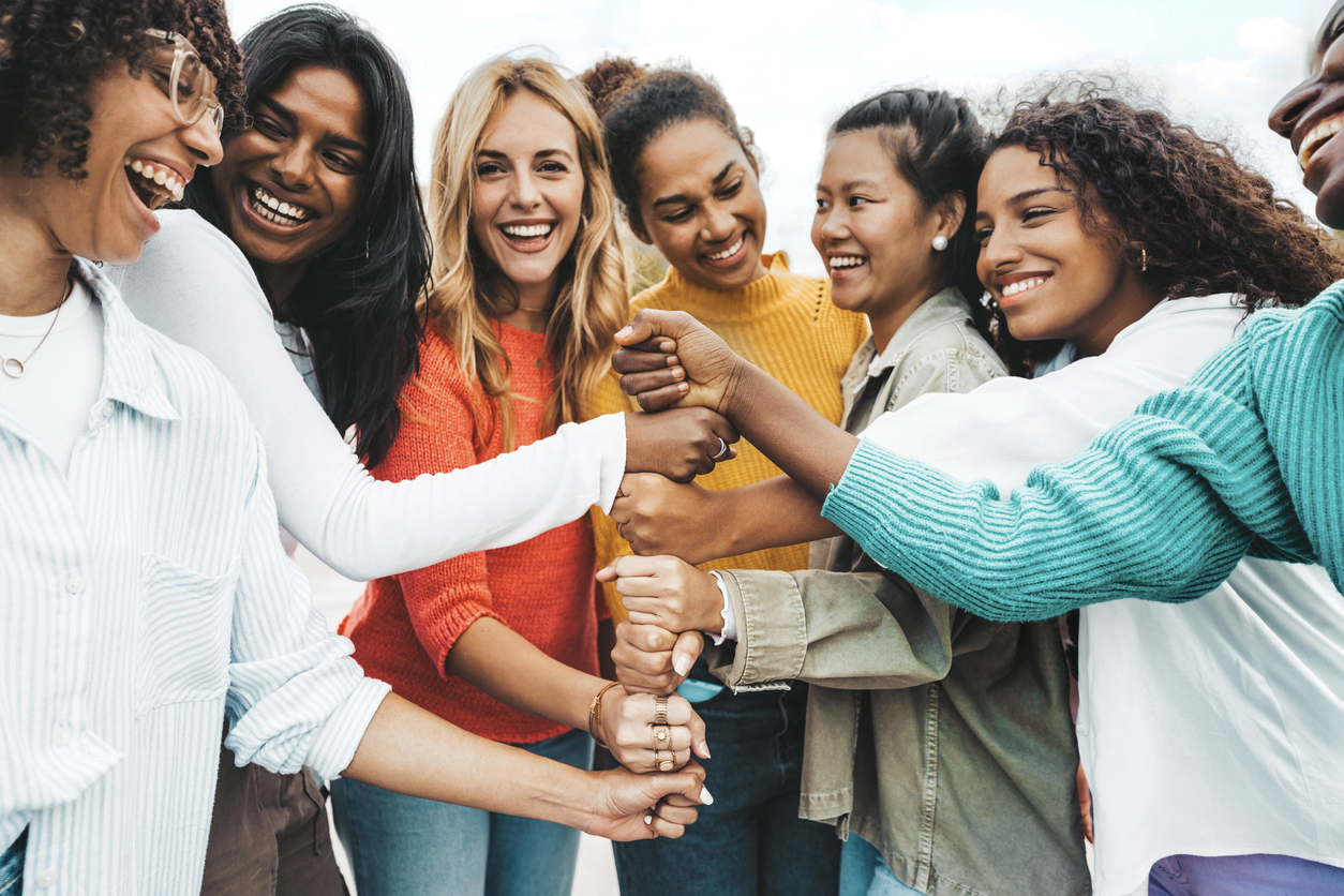 Diverse group of women stacking hands together in solidarity, community, and shared strength