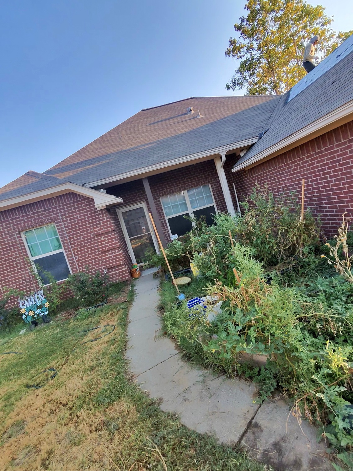 Brick home in North Texas with Roofing Glory crew on the roof