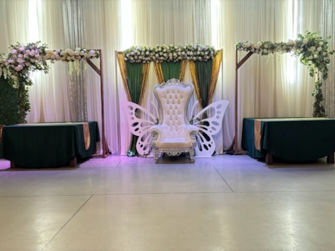 Royal butterfly wing throne chair with floral arches and green drapery backdrop