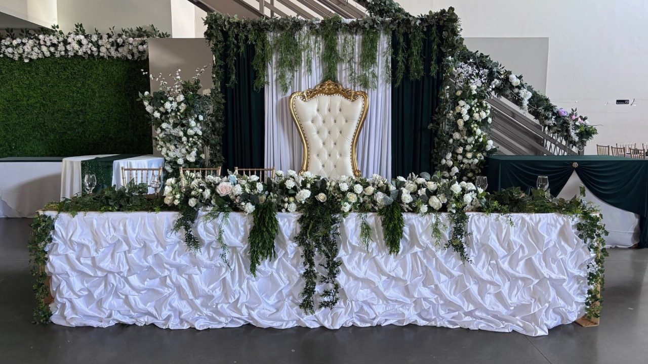 Luxurious gold tufted throne head table with cascading greenery and white rose florals