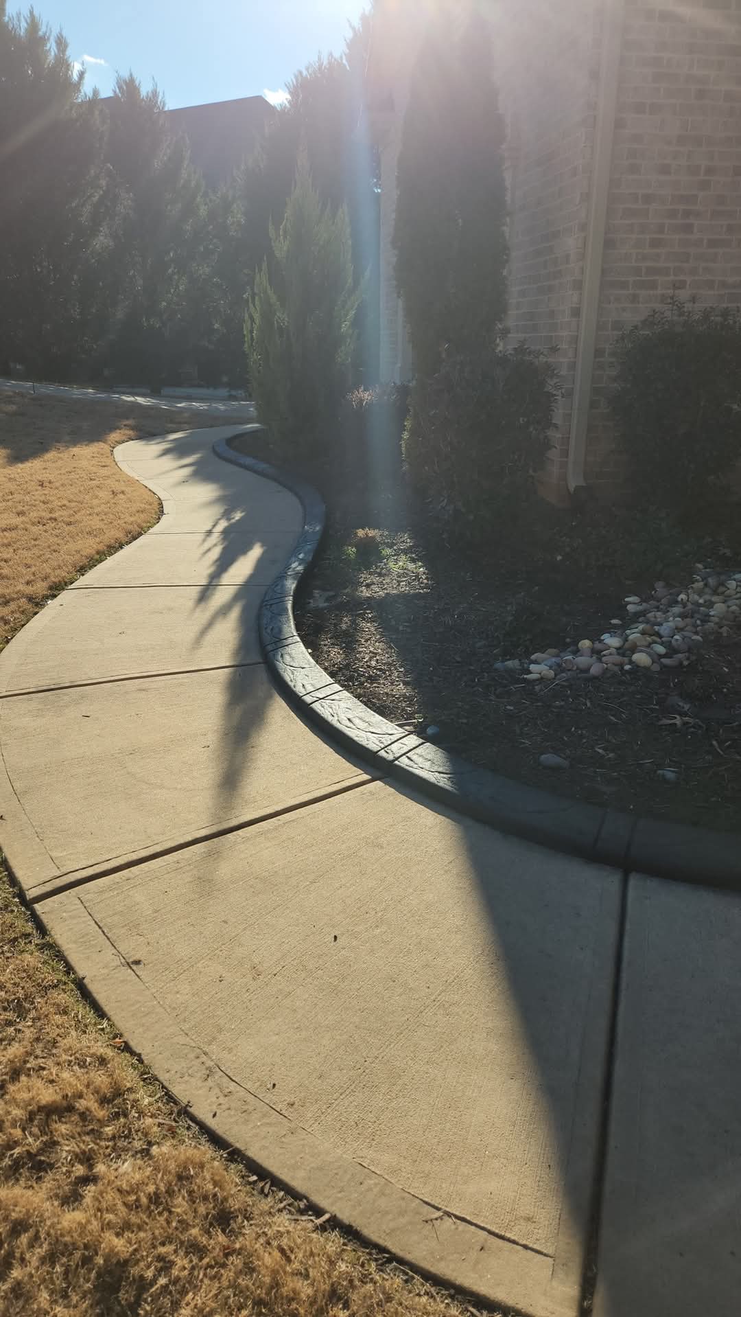 Decorative stamped curbing along curved concrete driveway with sun flare
