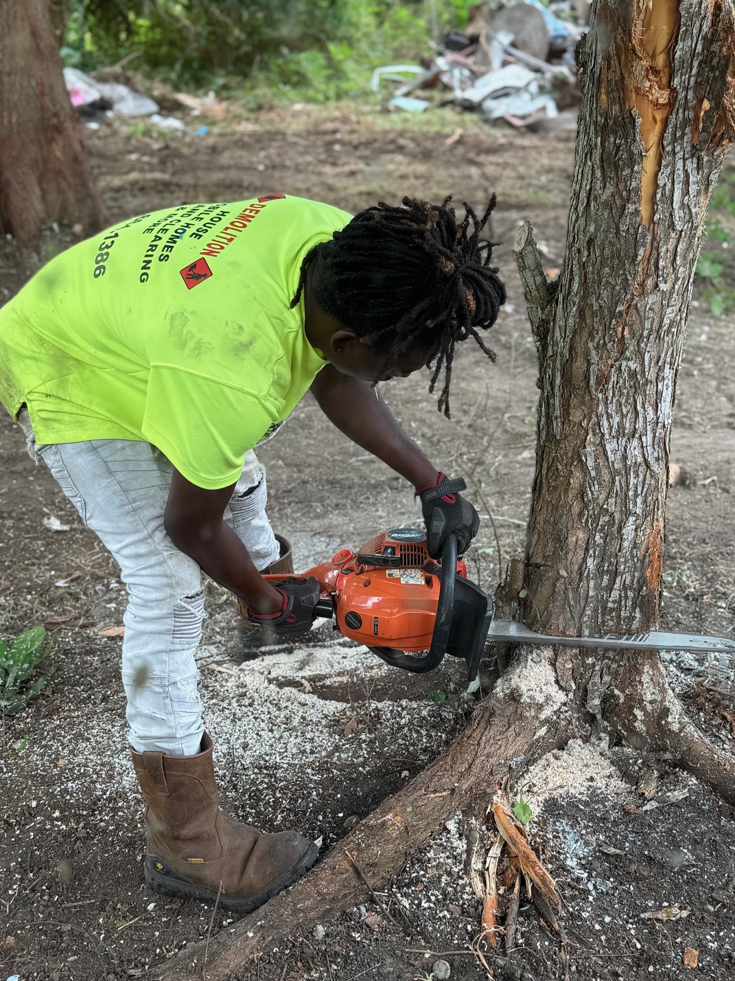 28 Blue Construction crew member performing tree removal with chainsaw
